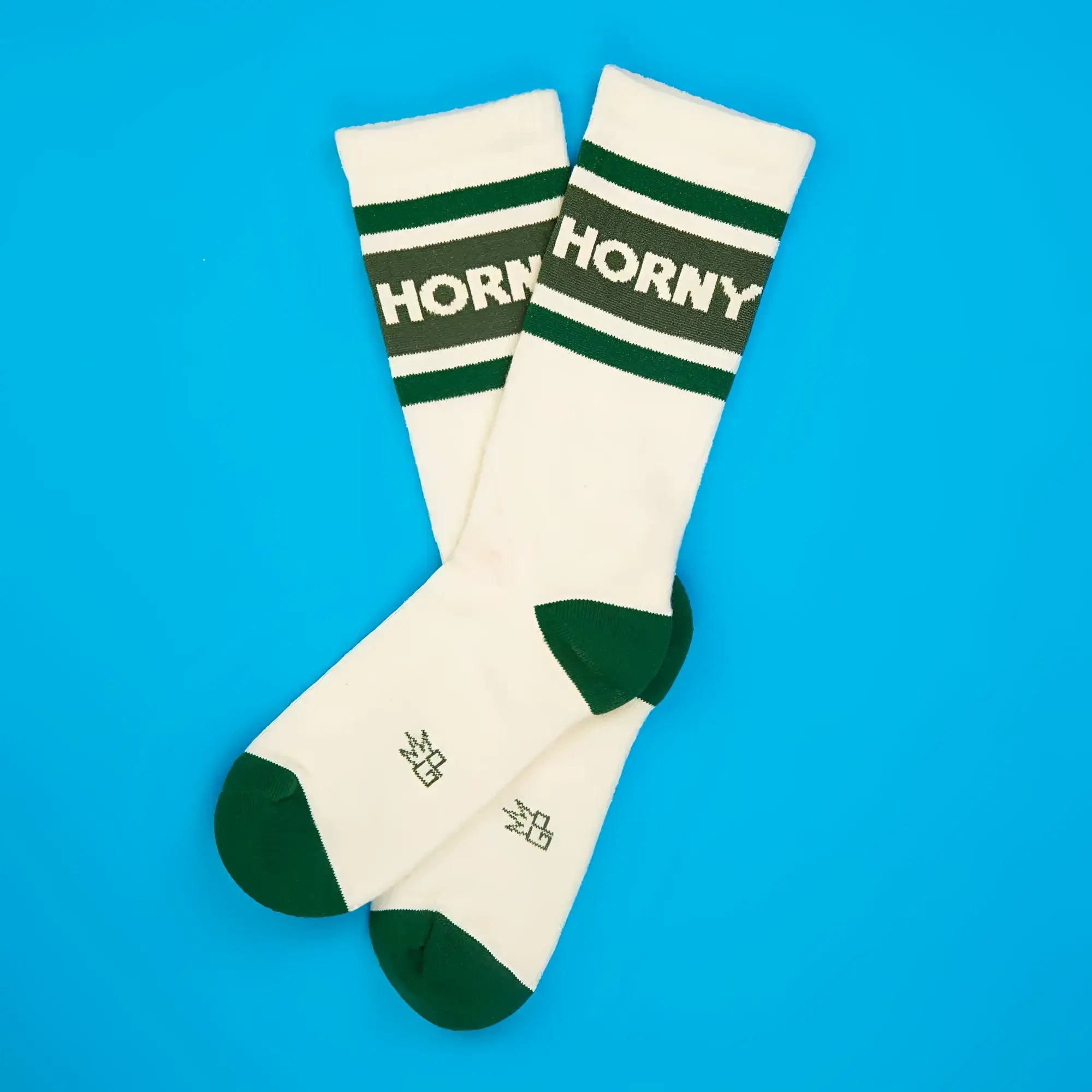 Cream-colored horny crew socks with dark green toe heel cuff and bold white logo on the top band