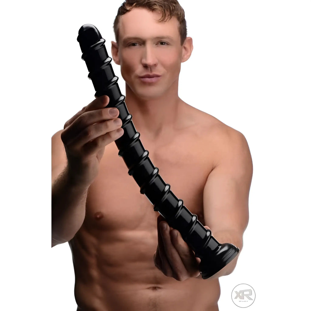 A shirtless man holds a long, thick, black 18-inch Hosed Swirl anal snake toy with a spiral-ribbed texture.
