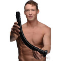 A shirtless man holds a long, black, realistic Hosed 19-inch anal dildo with a curved, textured design.