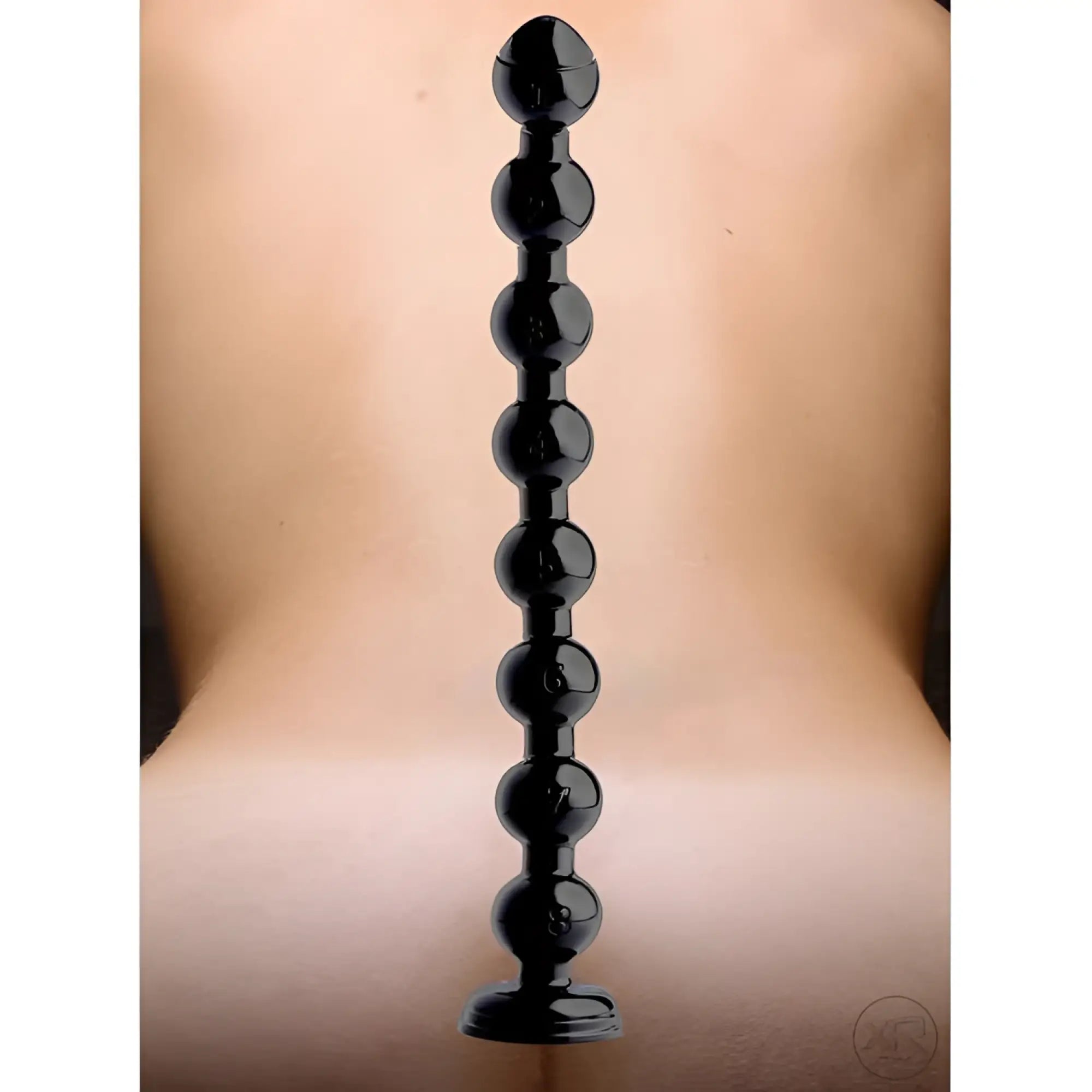 Hosed 2" Beaded Anal Snake: A long, black, graduated beaded toy shown centered against a blurred skin-toned background.