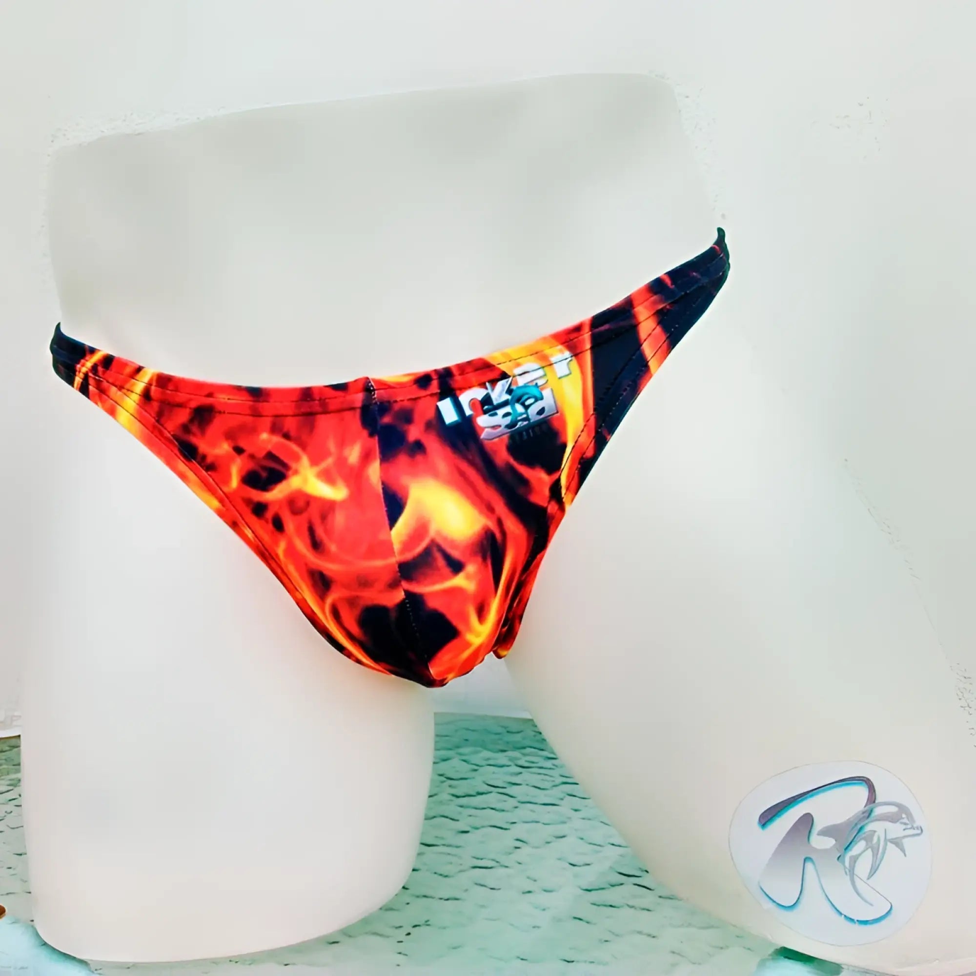 Icker Sea Fire Red thong underwear with vibrant red and orange flame-patterned swim trunks displayed on a mannequin