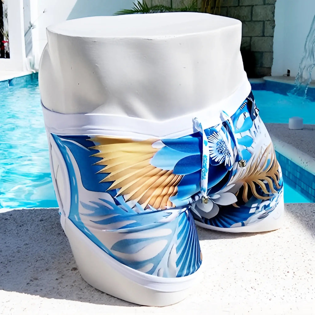 Icker Sea Greek Floral blue and white tropical print swim trunks with gold accents on a mannequin