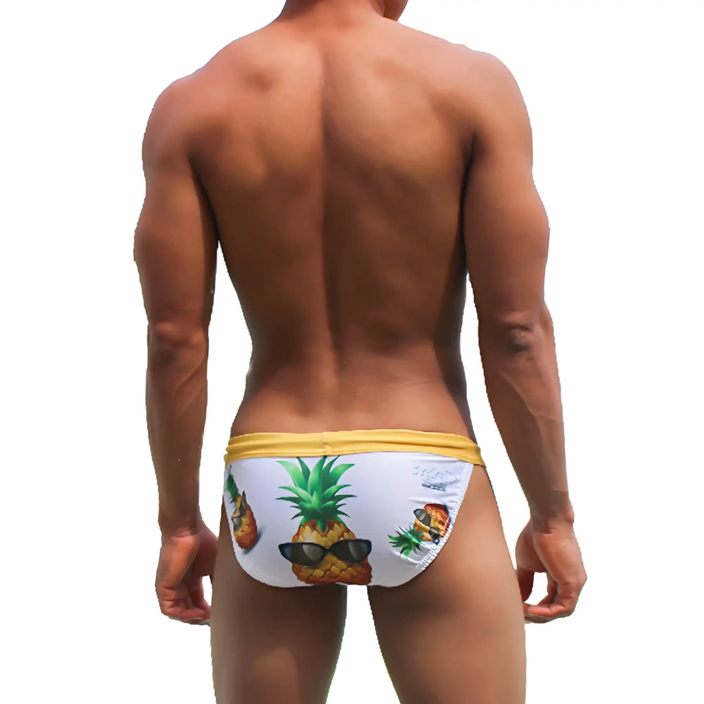 White swim trunks with yellow waistband and playful pineapple graphic wearing sunglasses from icker sea pineapples micro slip bikini swimwear cob-21-08