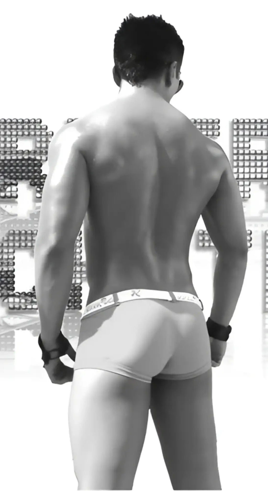 Black and white image of muscular man wearing icker sea sailor belted logo square cut trunk swimwear in green white