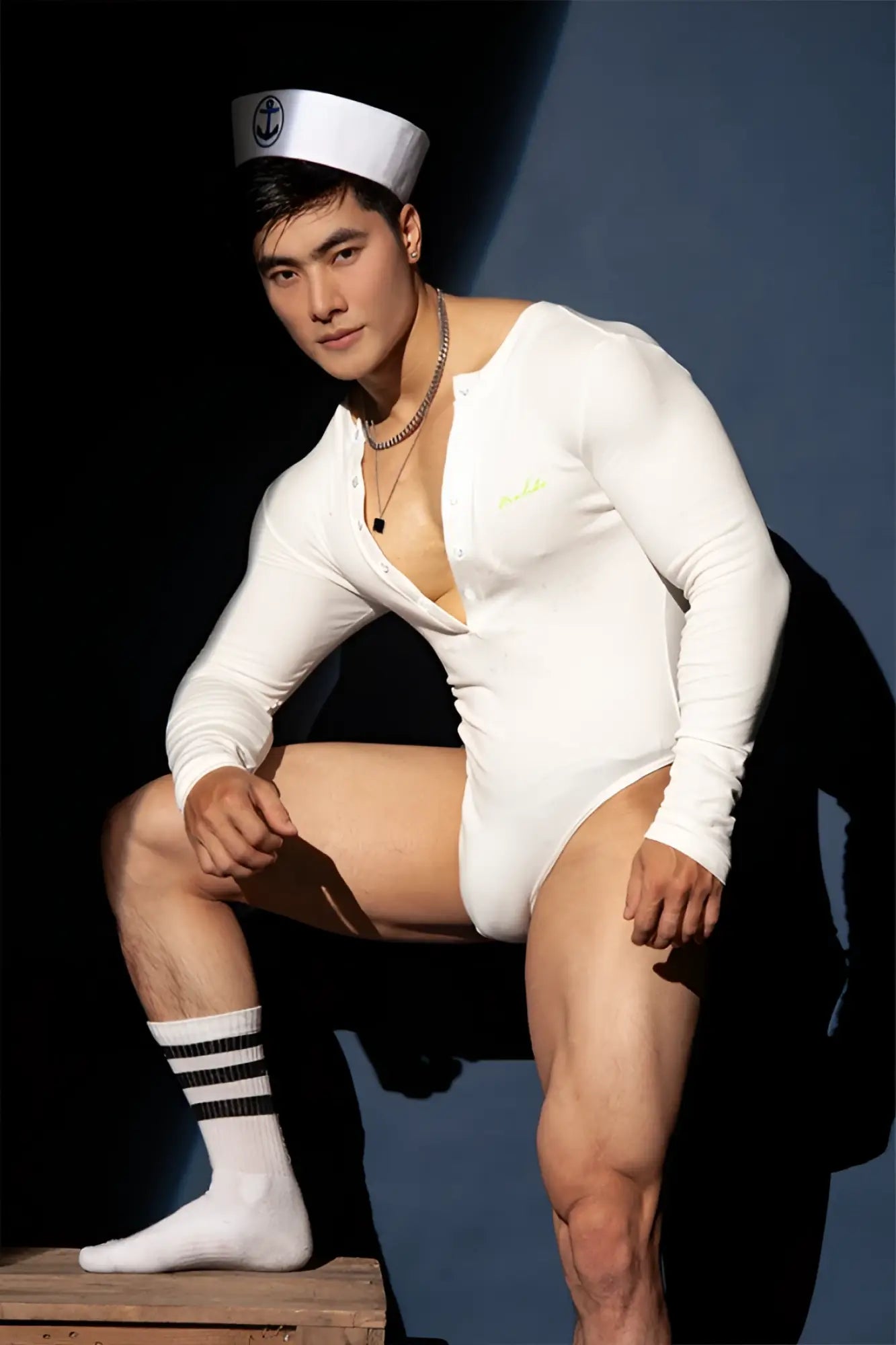 White infinity long sleeve button up bodysuit with a white sailor-style cap featuring a black anchor emblem