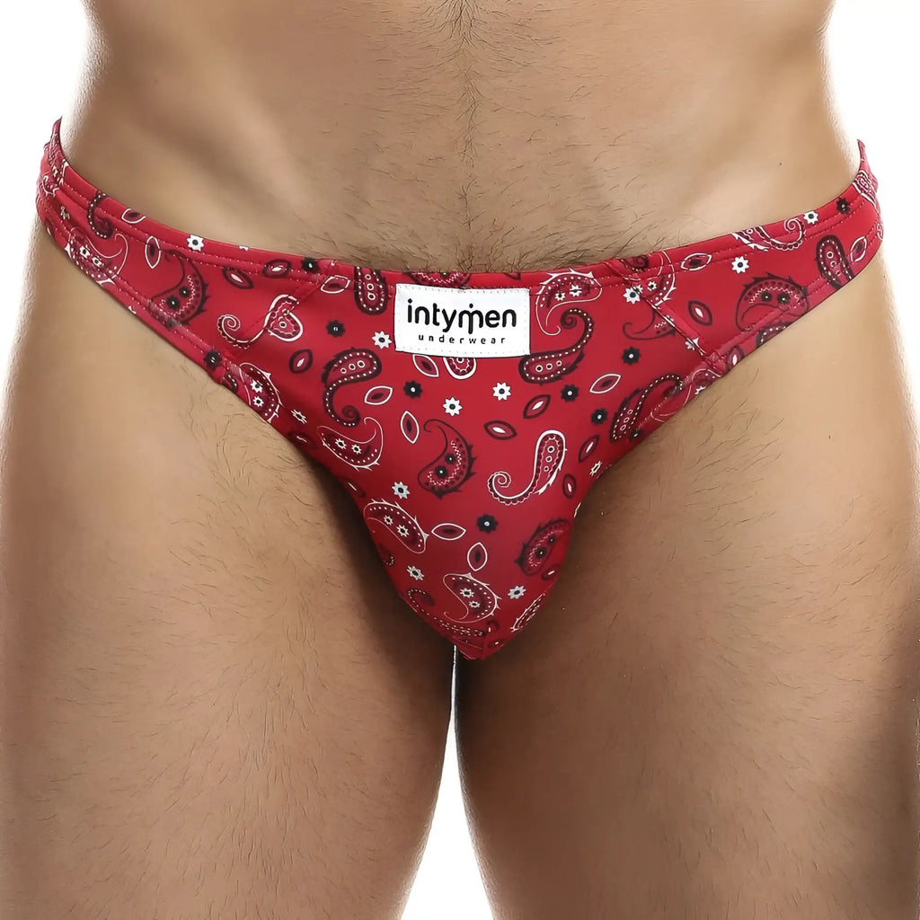 Red paisley-patterned men’s bikini briefs with black and white accents featuring intymen underwear brand label