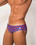 Ipanema Sunga men’s designer swimwear featuring blue and red geometric patterned swim trunks with white dog logo