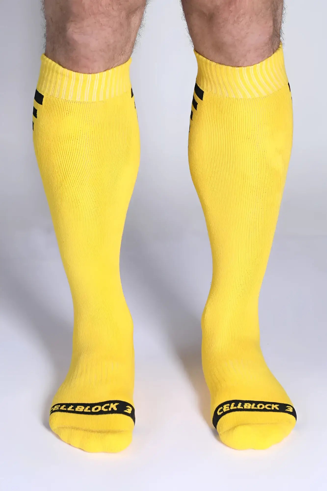 Iron Grip knee high socks in bright yellow with black cuff stripes and Cellblock 3 branding at the toe