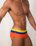 Itacoatiara Trio sunga designer swim shorts with vibrant orange fabric and a bold yellow and blue striped waistband