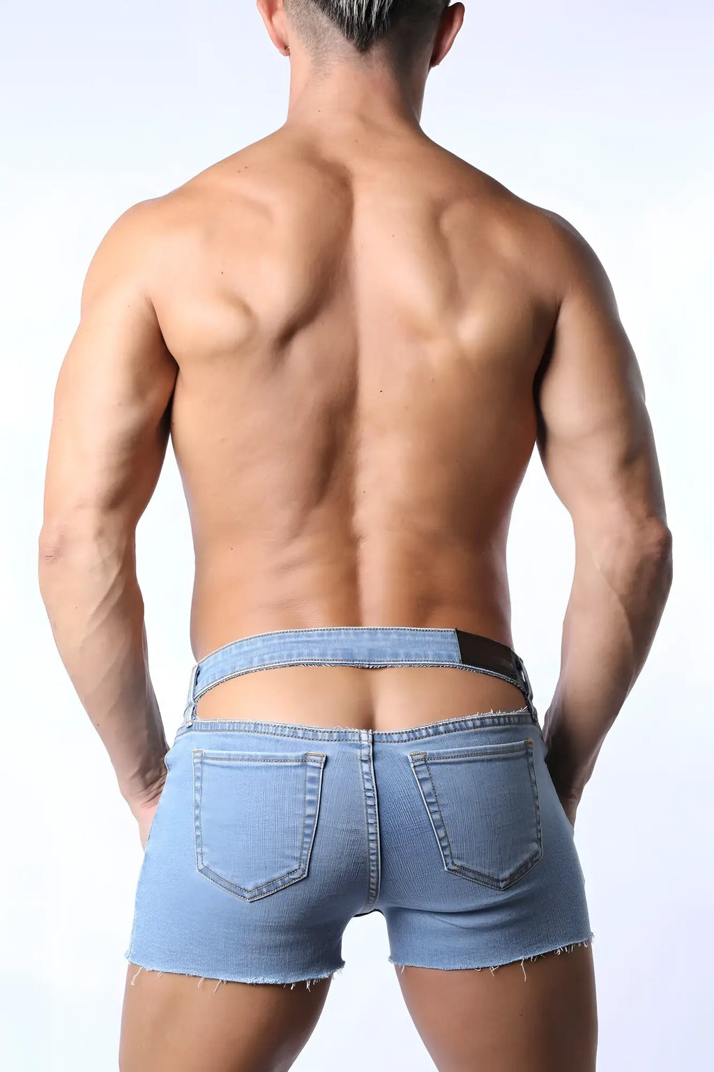 Light-wash denim j-flo peek-a-boo booty shorts with frayed hem and open back design shown from the back side
