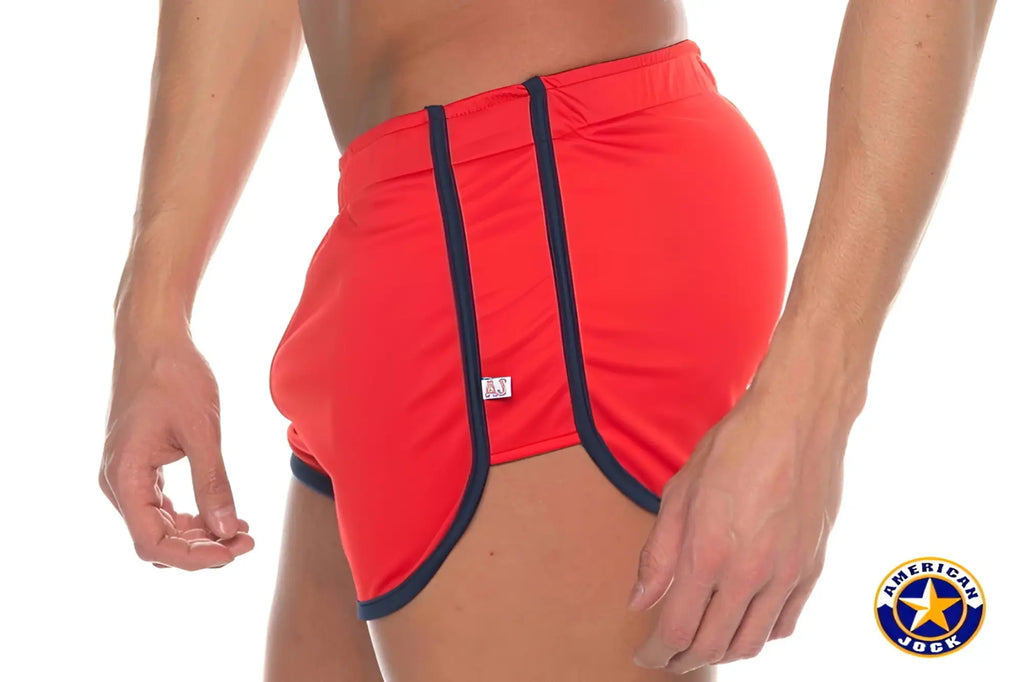 Red A J Phys Ed track shorts with navy blue trim and a small white brand tag for athletic use
