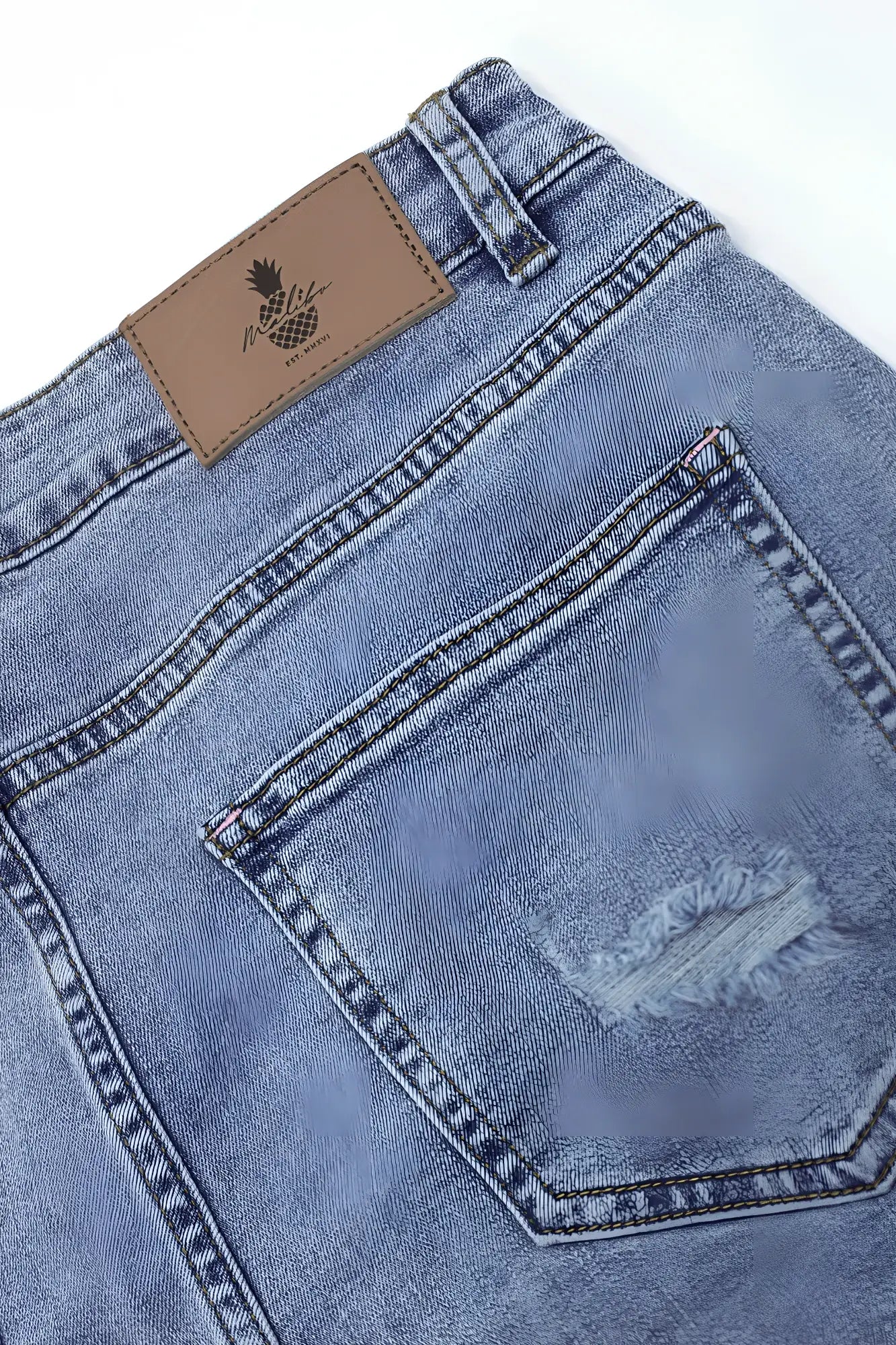 Back side of jaded 3.5 inch denim short shorts in washed blue featuring a distressed pocket and brown pineapple patch