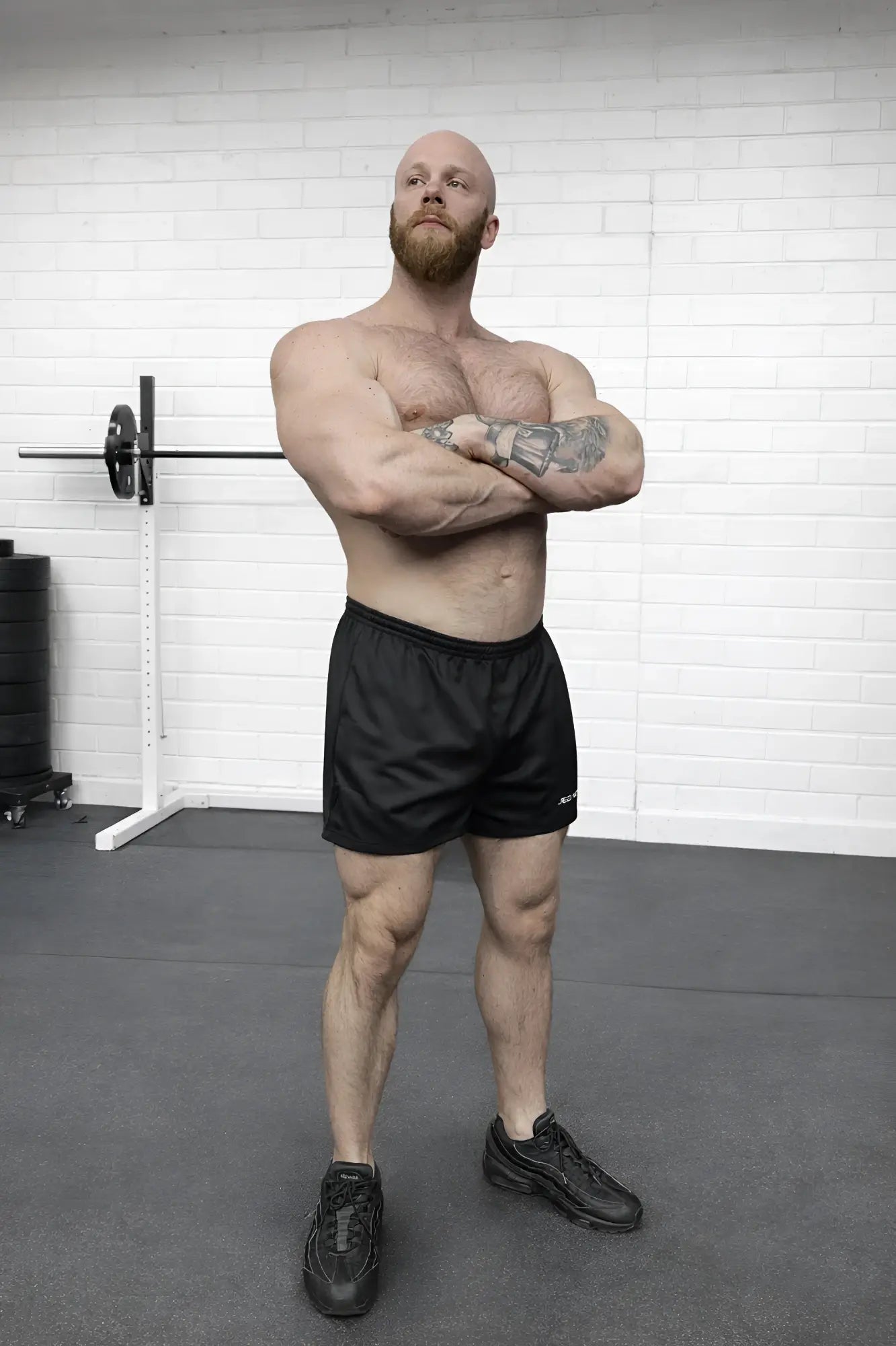 A muscular man with a bald head and red beard wearing black 5 inch double layer mesh basketball shorts in a gym