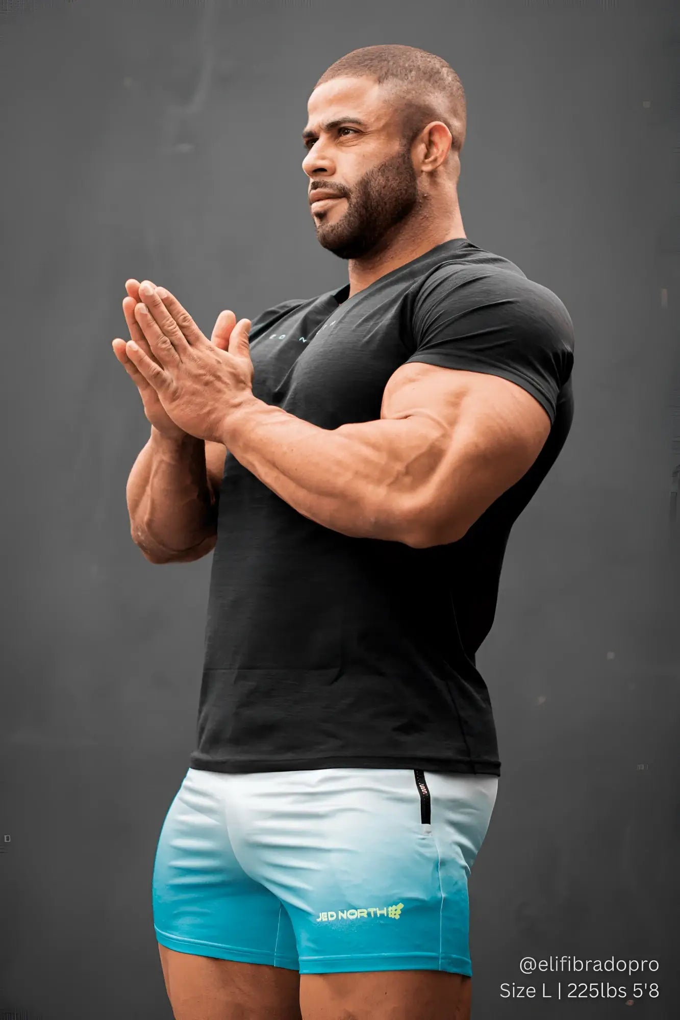 Black short-sleeved v-neck t-shirt with subtle texture and small green logo paired with jed north agile bodybuilding 4 inch blue ombre shorts with zipper pockets