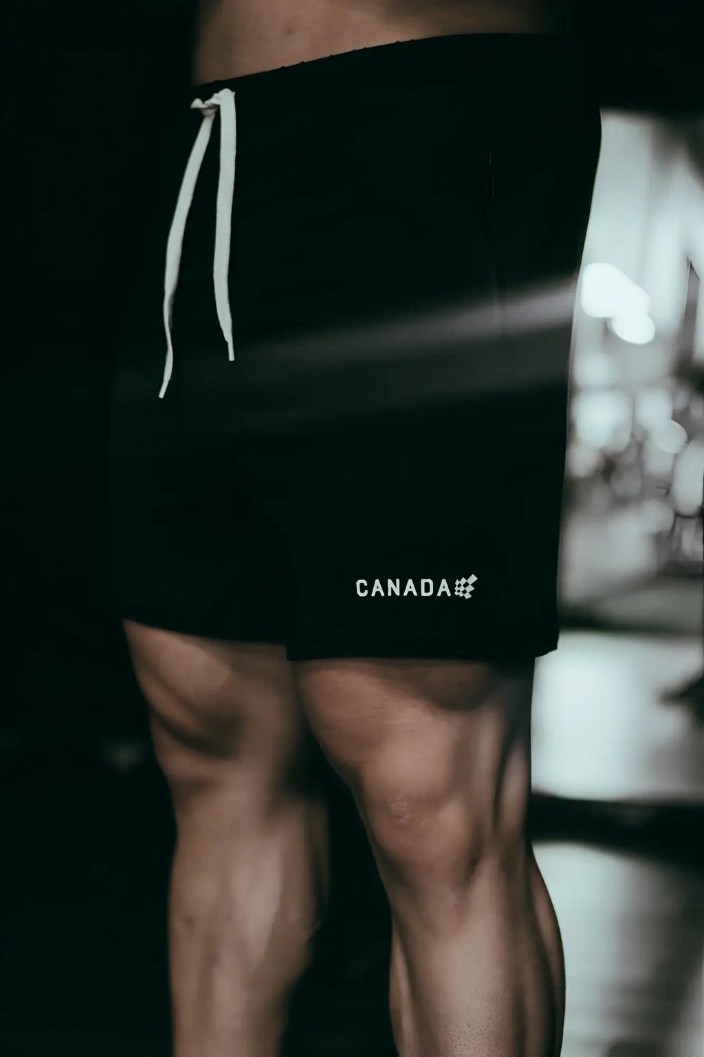 Black agile bodybuilding 4 inch athletic shorts with white drawstrings and canada logo on lower left leg with zipper pockets