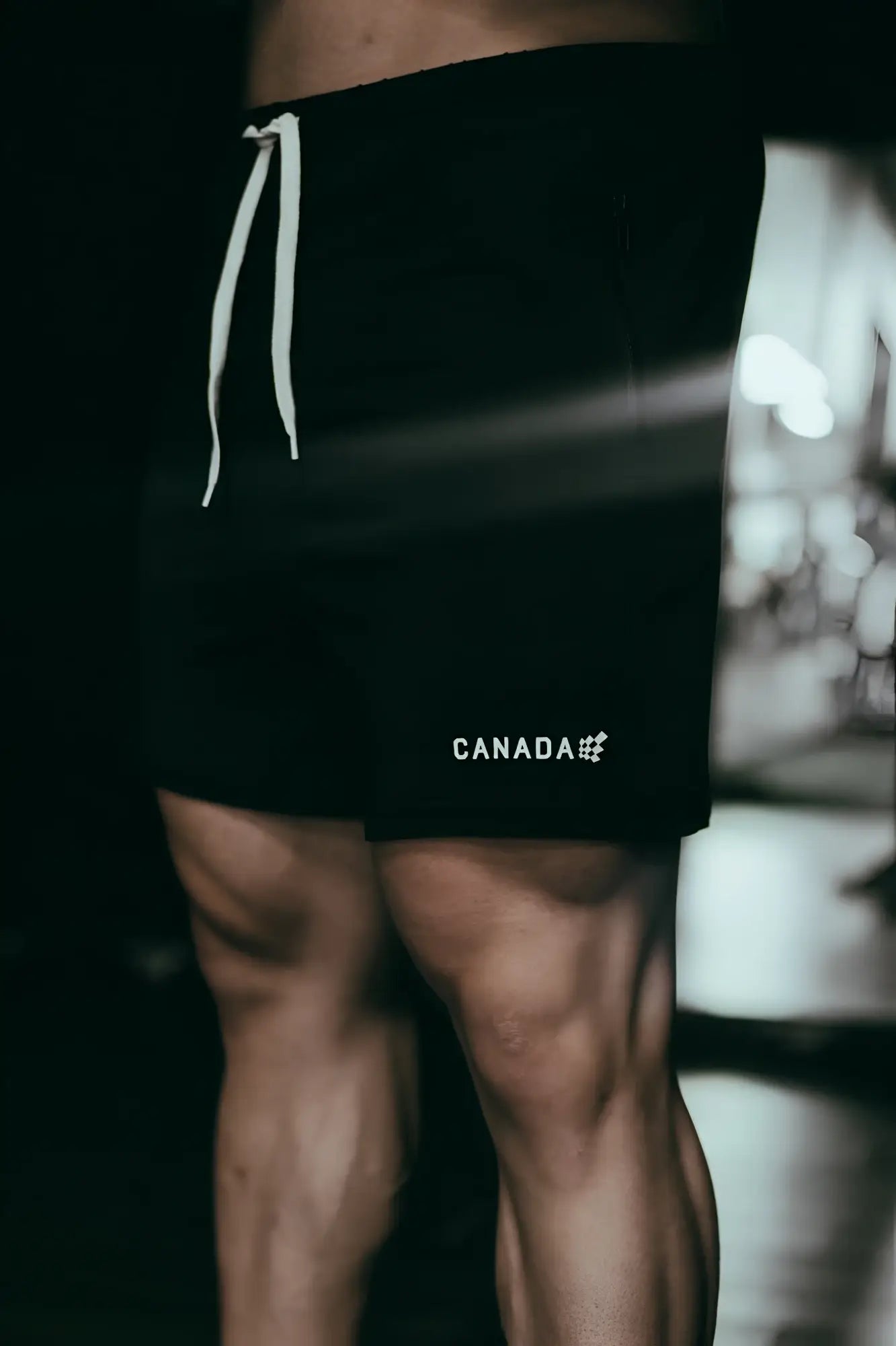 Black agile bodybuilding 4 inch athletic shorts with white drawstrings and canada logo on lower left leg with zipper pockets