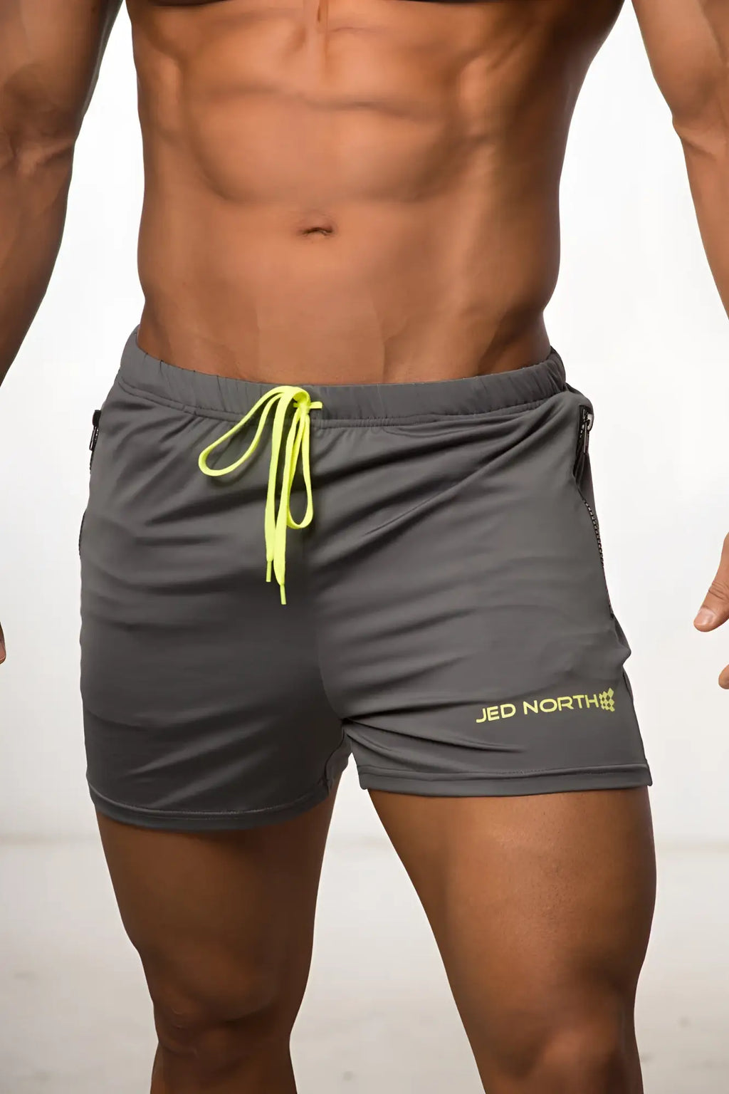 Gray jed north agile bodybuilding 4 inch shorts with neon yellow drawstring zipper pockets and logo on lower right leg