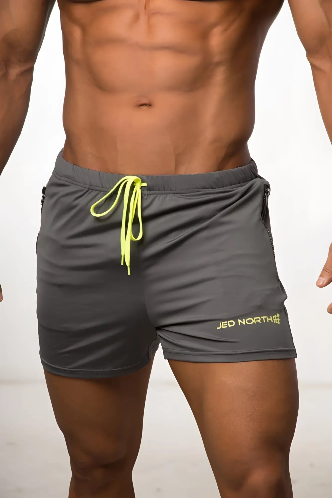 Gray jed north agile bodybuilding 4 inch shorts with neon yellow drawstring zipper pockets and logo on lower right leg