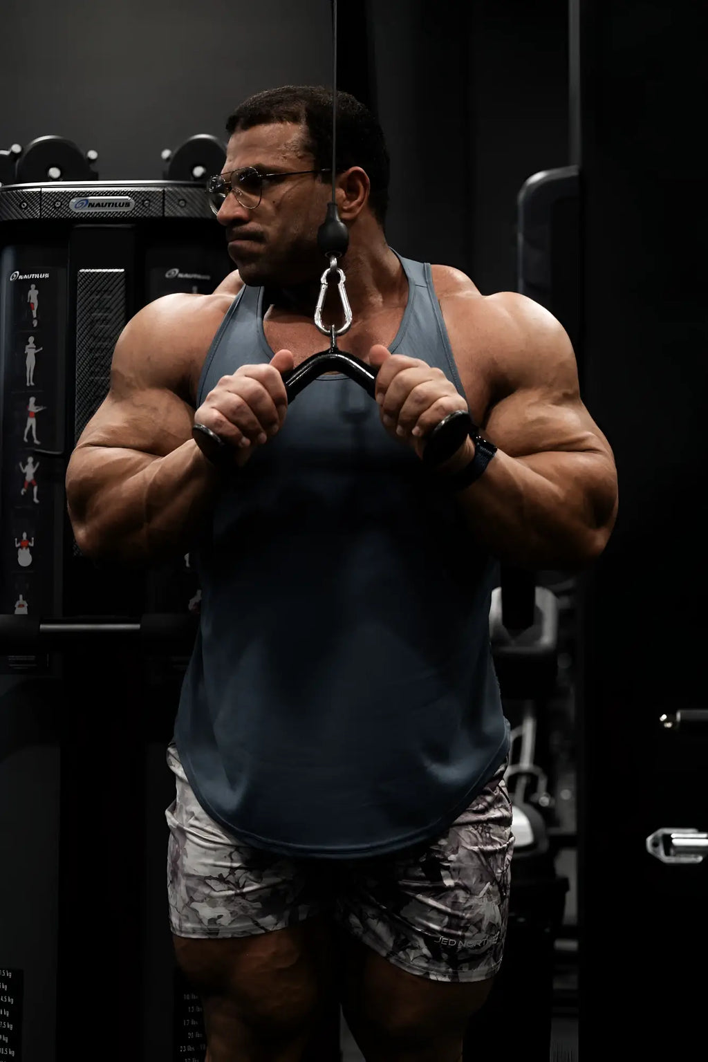 Muscular man wearing dark gray tank top and agile bodybuilding 4 inch leaf camo shorts with zipper pockets
