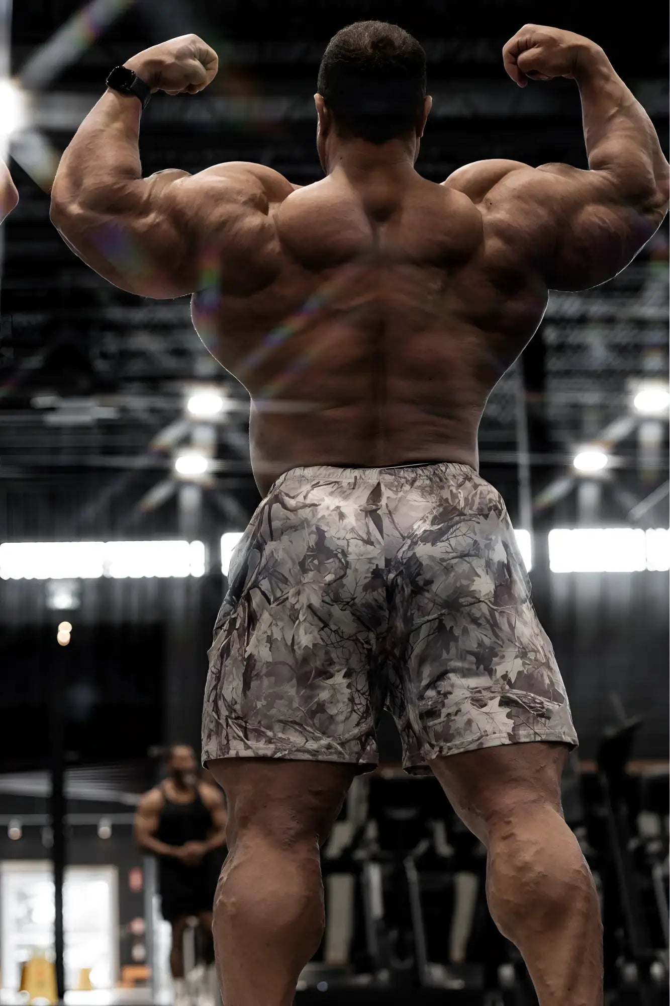 A muscular man wearing agile bodybuilding 4 inch leaf camo shorts with zipper pockets showing front view