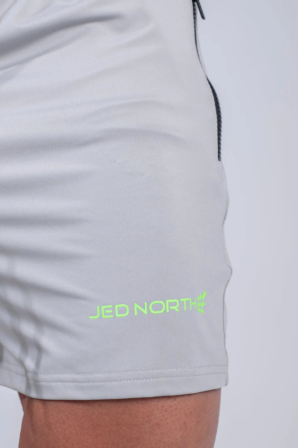 Light gray Jed North agile bodybuilding shorts with neon green logo and black zipper pockets in platinum gray