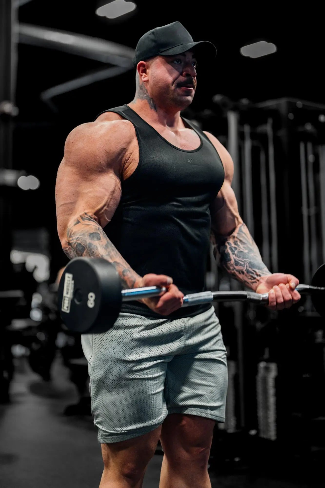 Black weight plate with silver barbell handle alongside jed north alpha microfiber fast-dry gym tank top in obsidian black