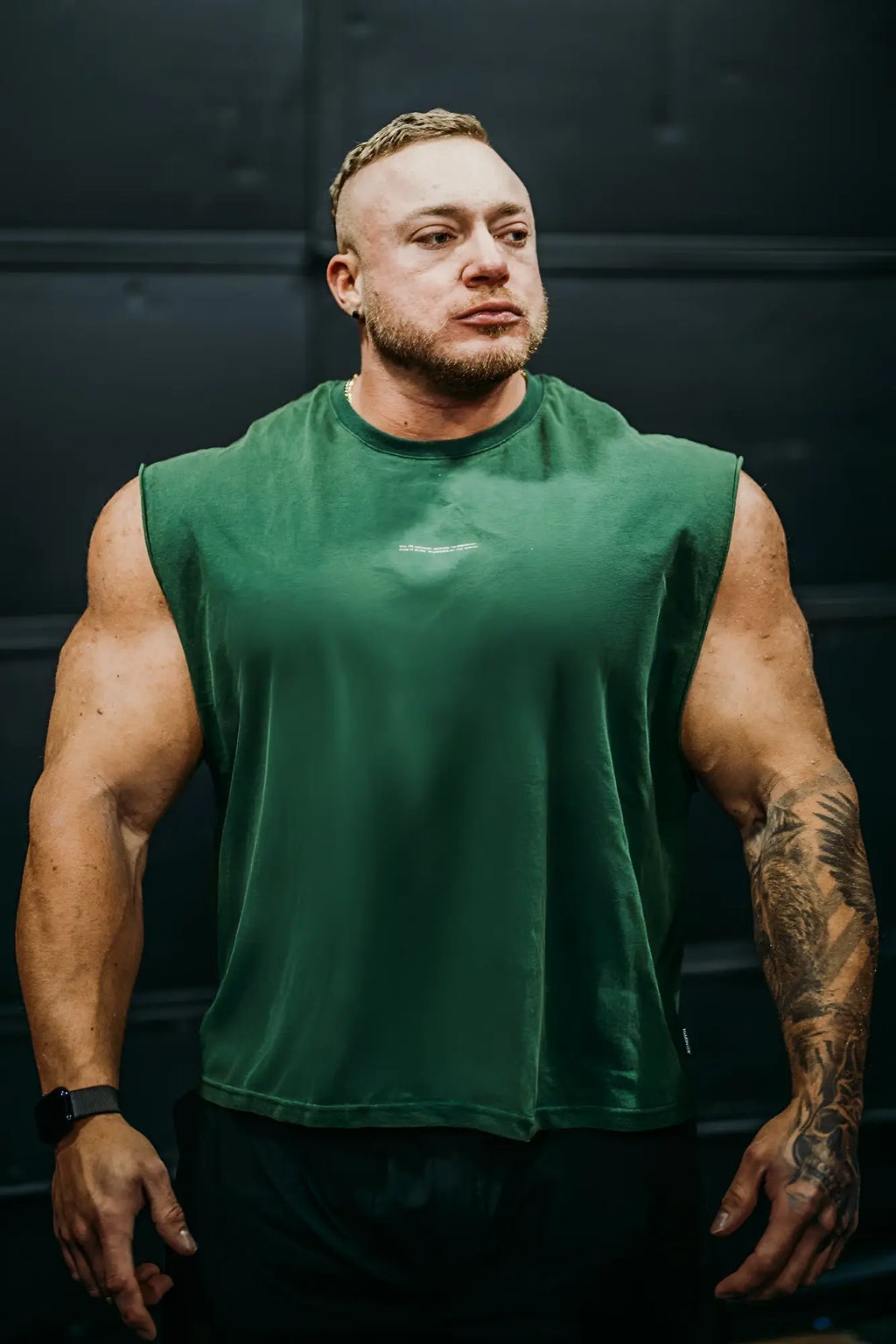 A dark green sleeveless cotton box cut muscle tee with a subtle white logo on the chest