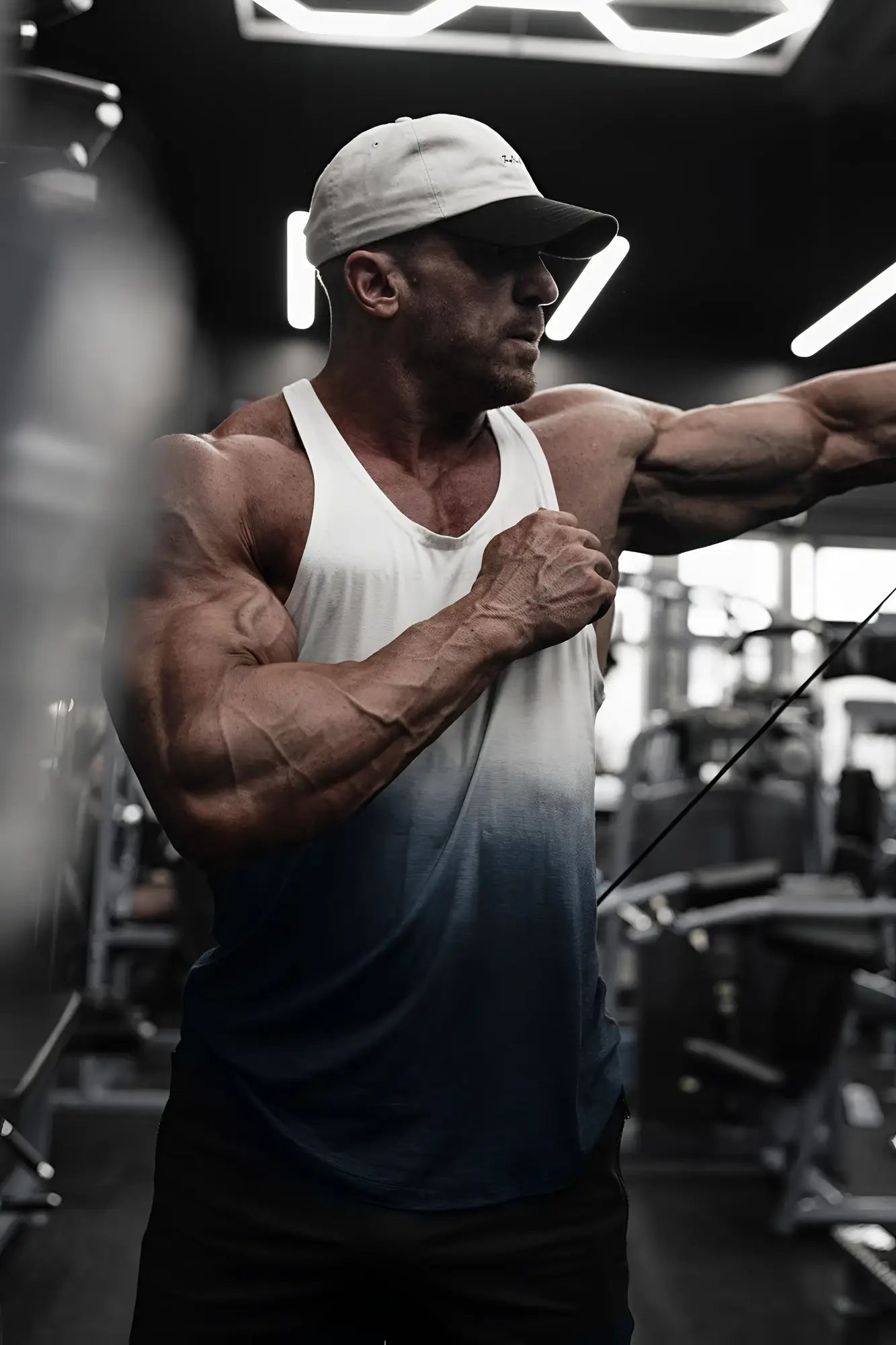 A muscular man wearing a classic bodybuilding racerback stringer tank top in black ombre gradient colors