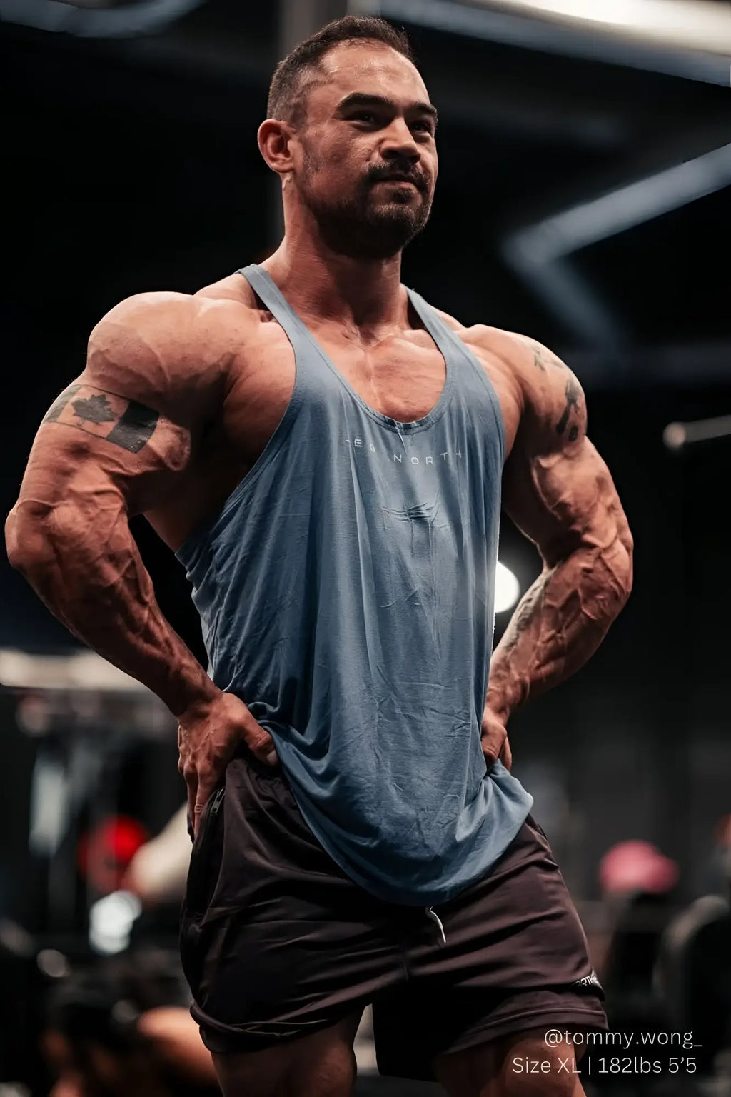 A muscular man wearing a faded blue Jed North classic bodybuilding racerback stringer tank top with strength print