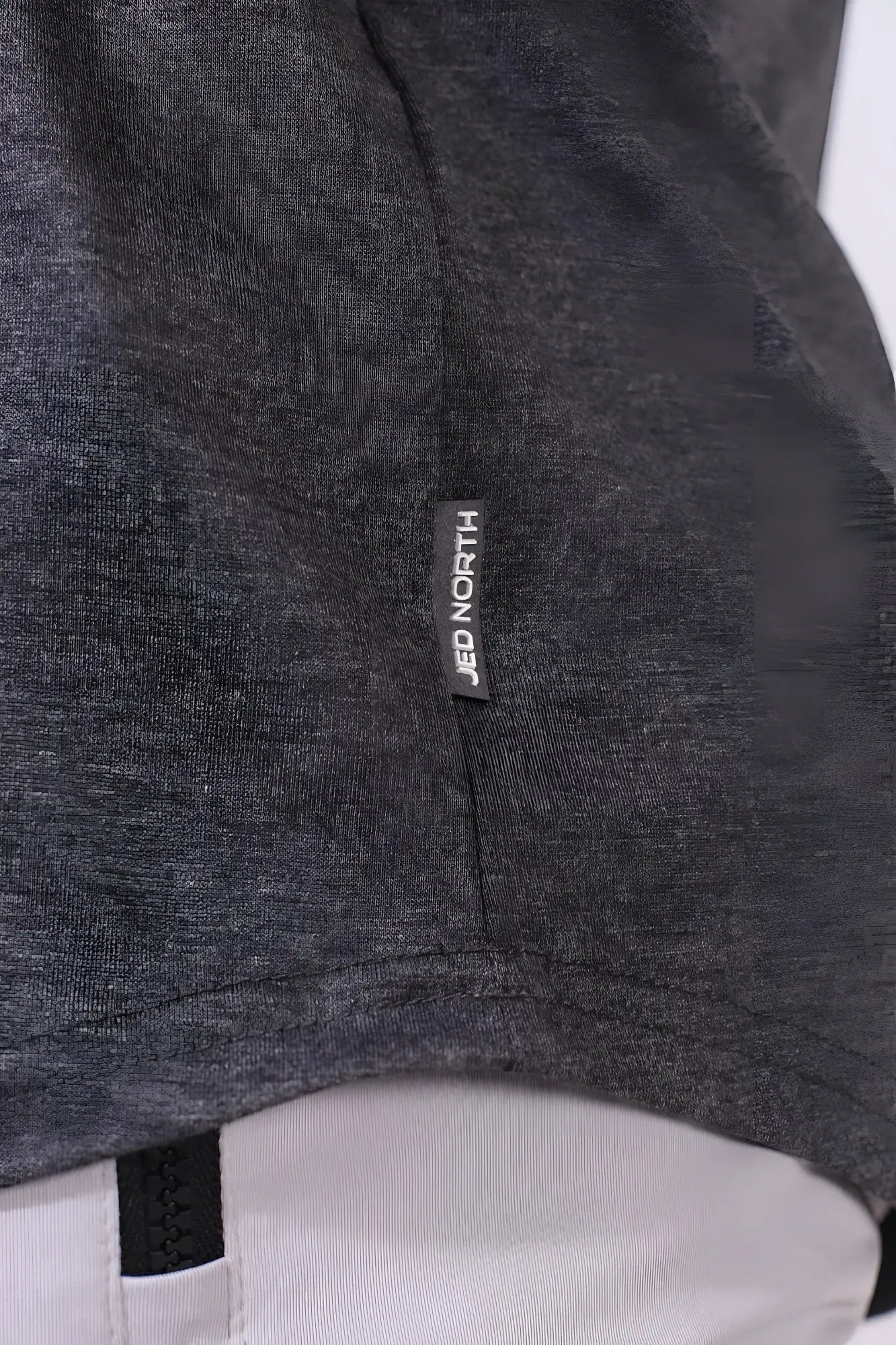 Dark gray heathered fabric of jed north classic bodybuilding racerback stringer with black brand tag near seam