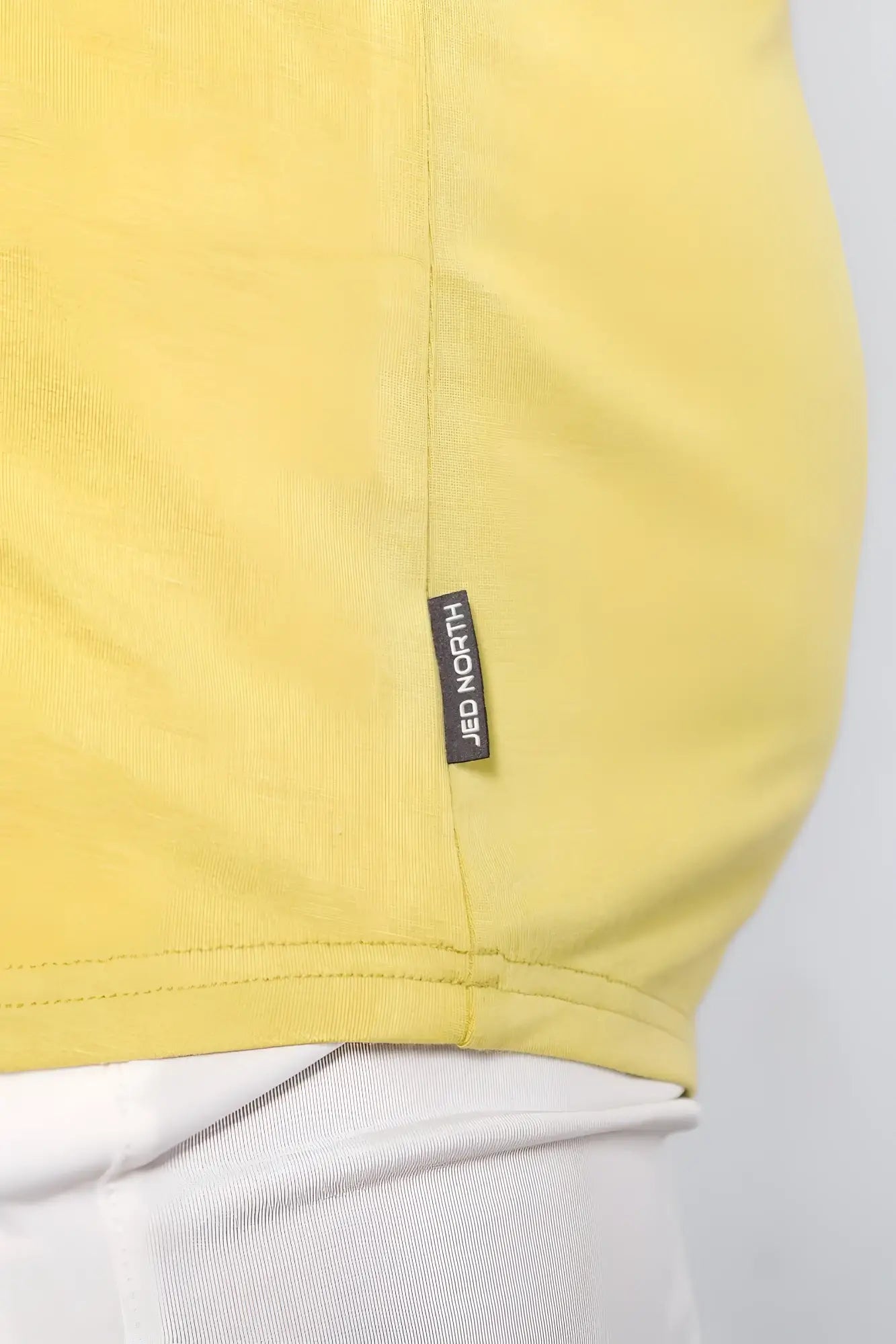 A vibrant yellow cotton jed north classic bodybuilding racerback stringer with a black brand tag near the hem
