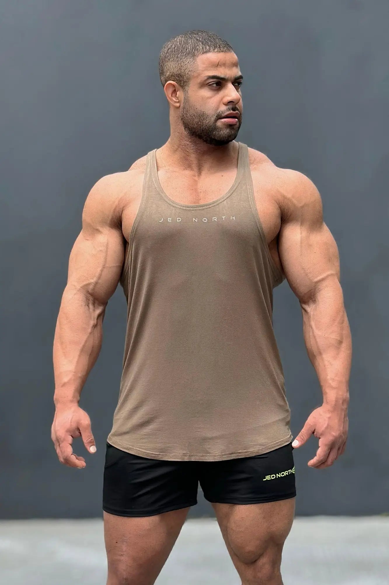Tan sleeveless tank top with jed north branding across the chest from the jed north classic bodybuilding racerback stringer olive collection
