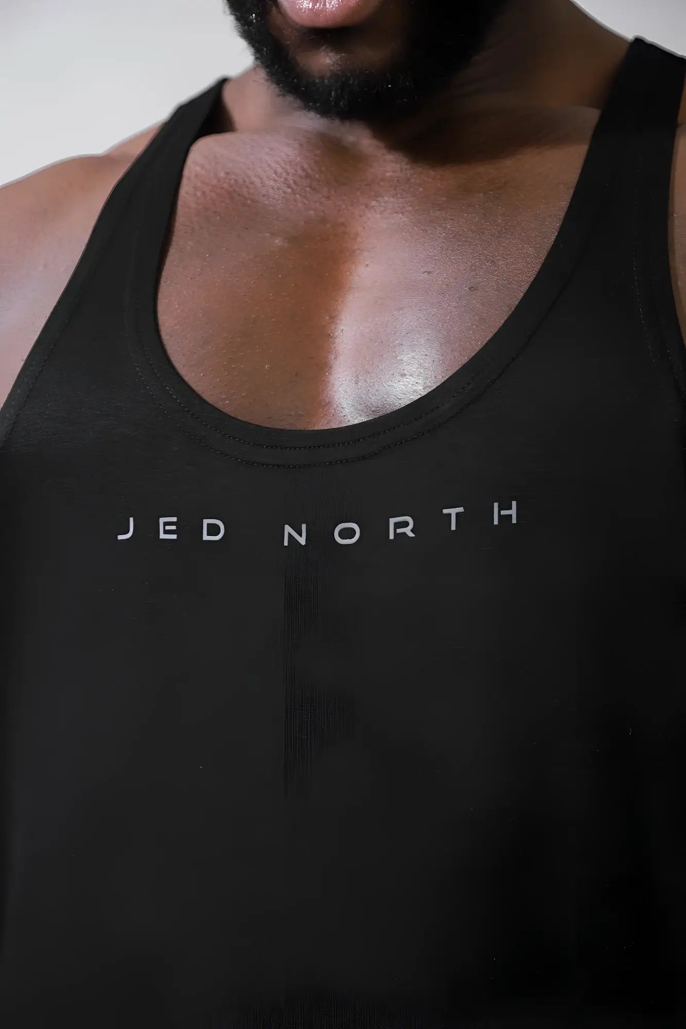 Black premium Jed North classic bodybuilding racerback stringer tank top with silver Jed North lettering on chest