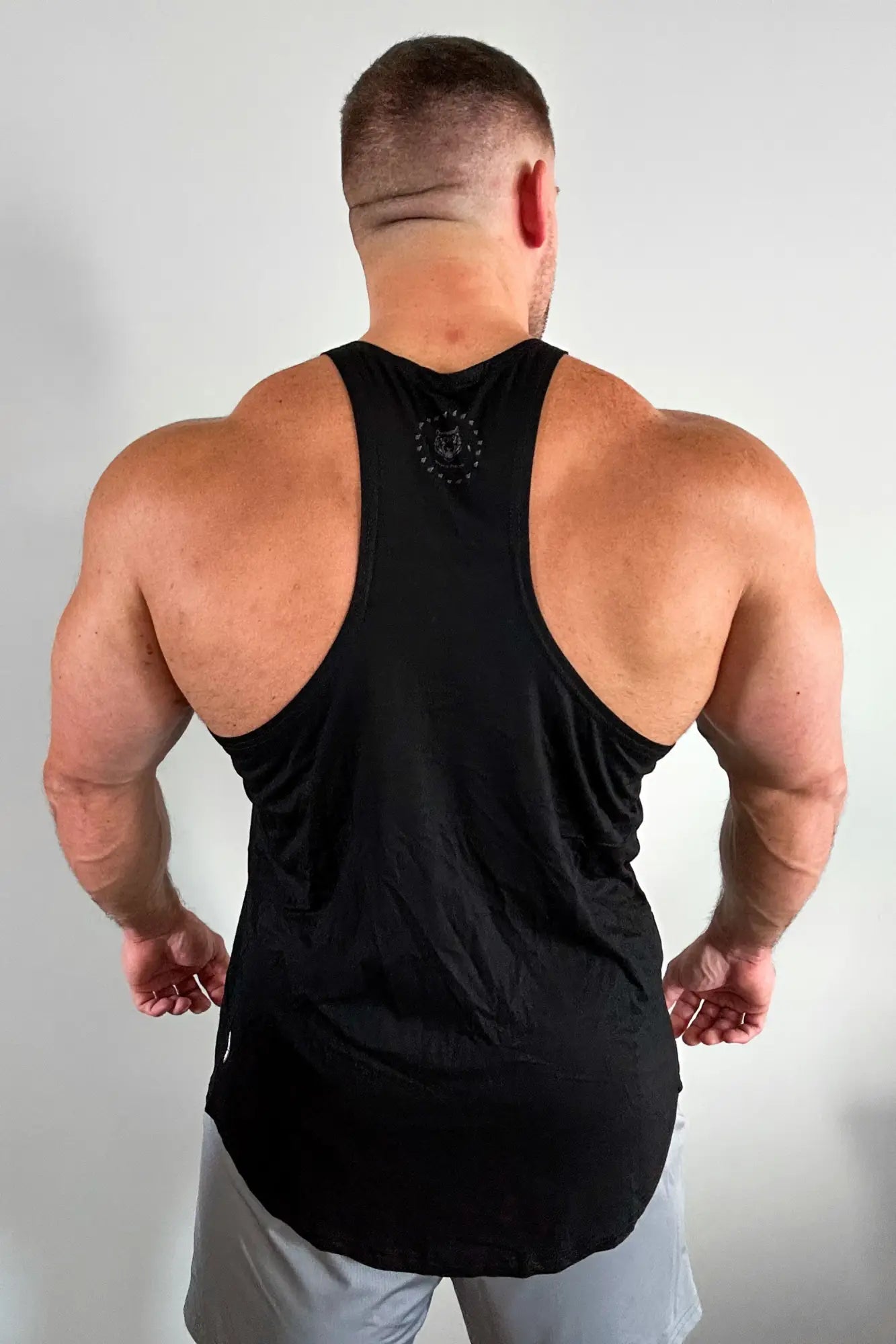 Black classic bodybuilding racerback stringer muscle tank top with subtle circular logo at the neckline