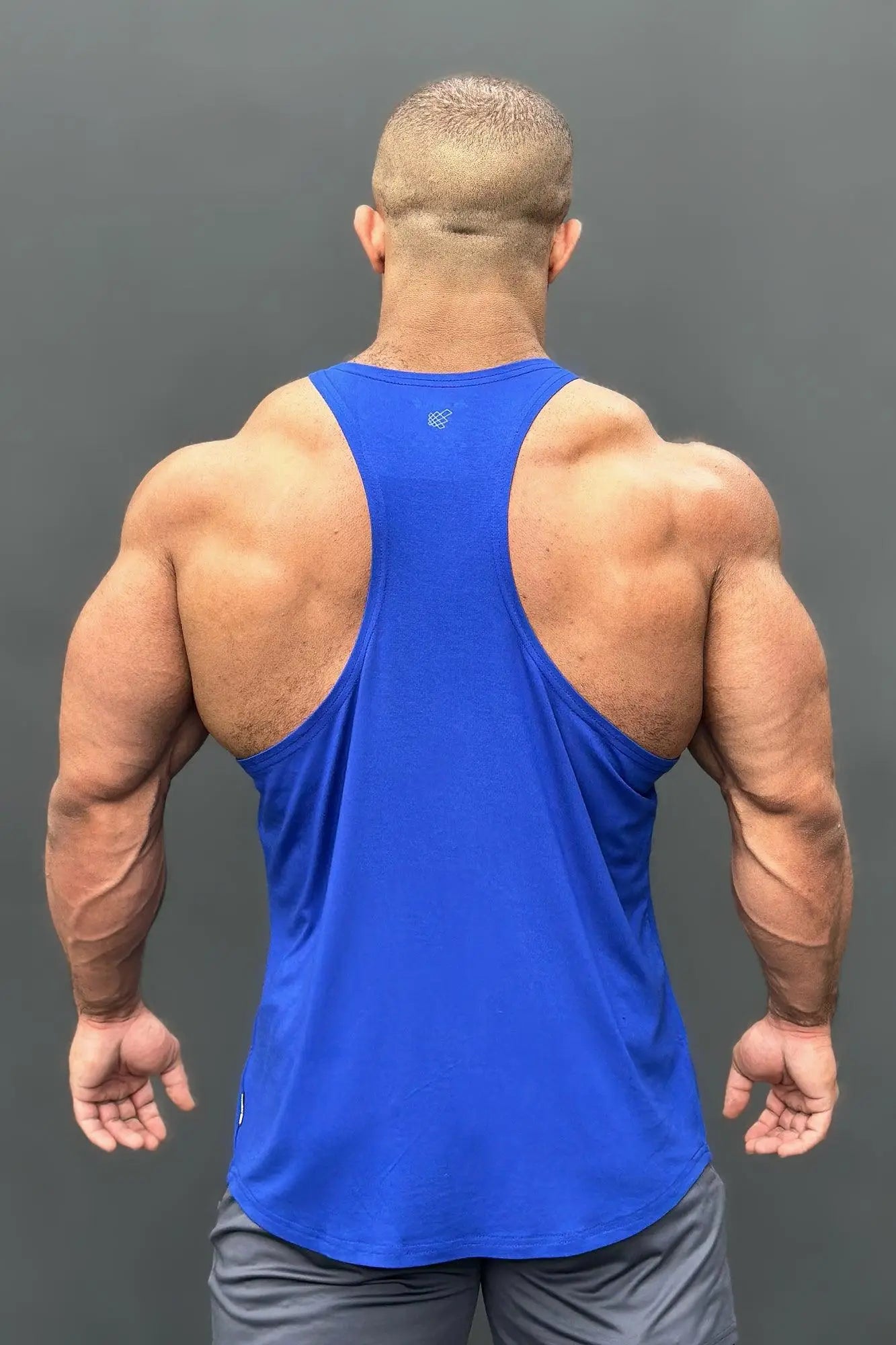 Blue athletic tank top with racerback design and small logo on upper back shown from back side