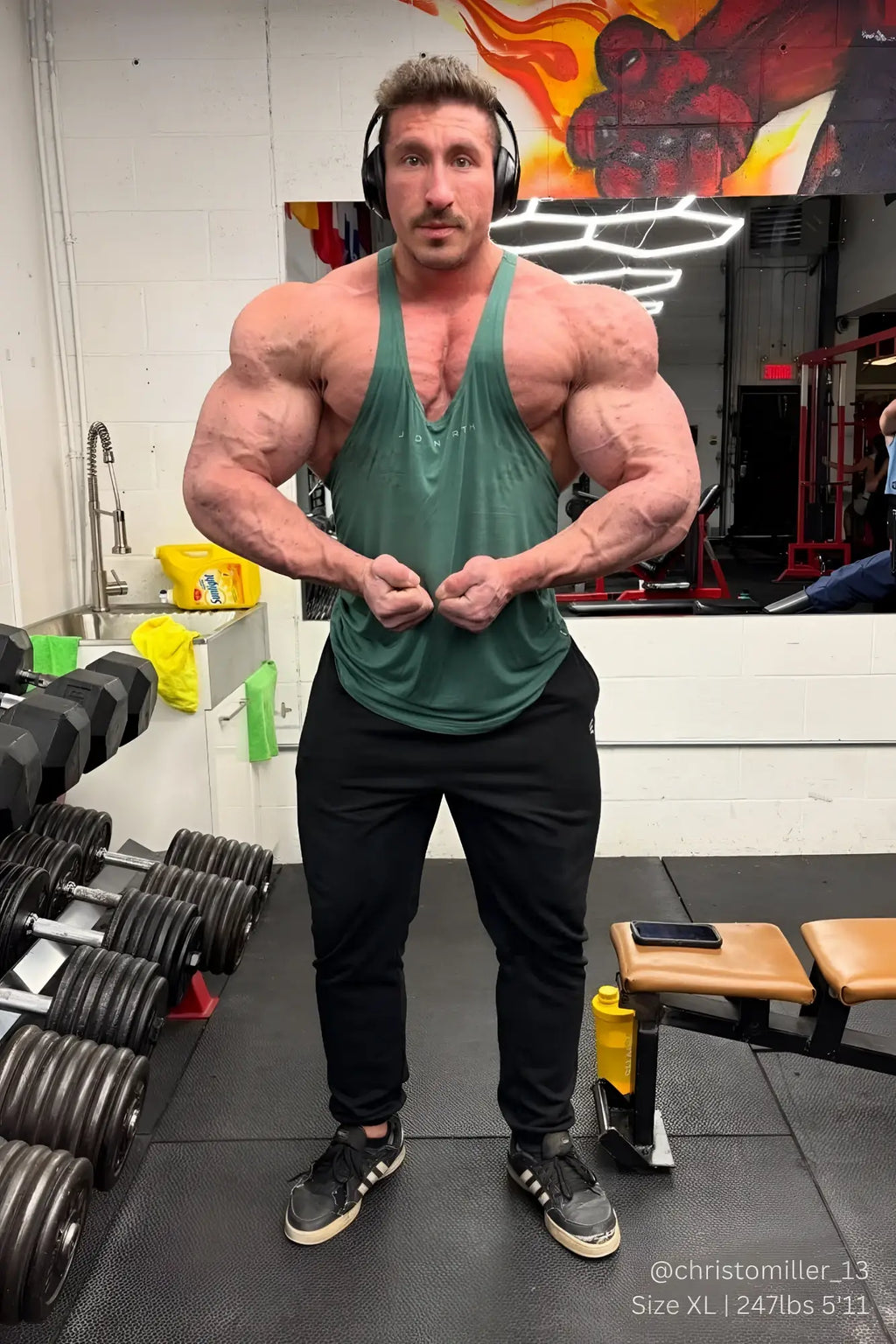 Muscular man wearing a sea green classic bodybuilding racerback stringer tank top in a front view with black pants
