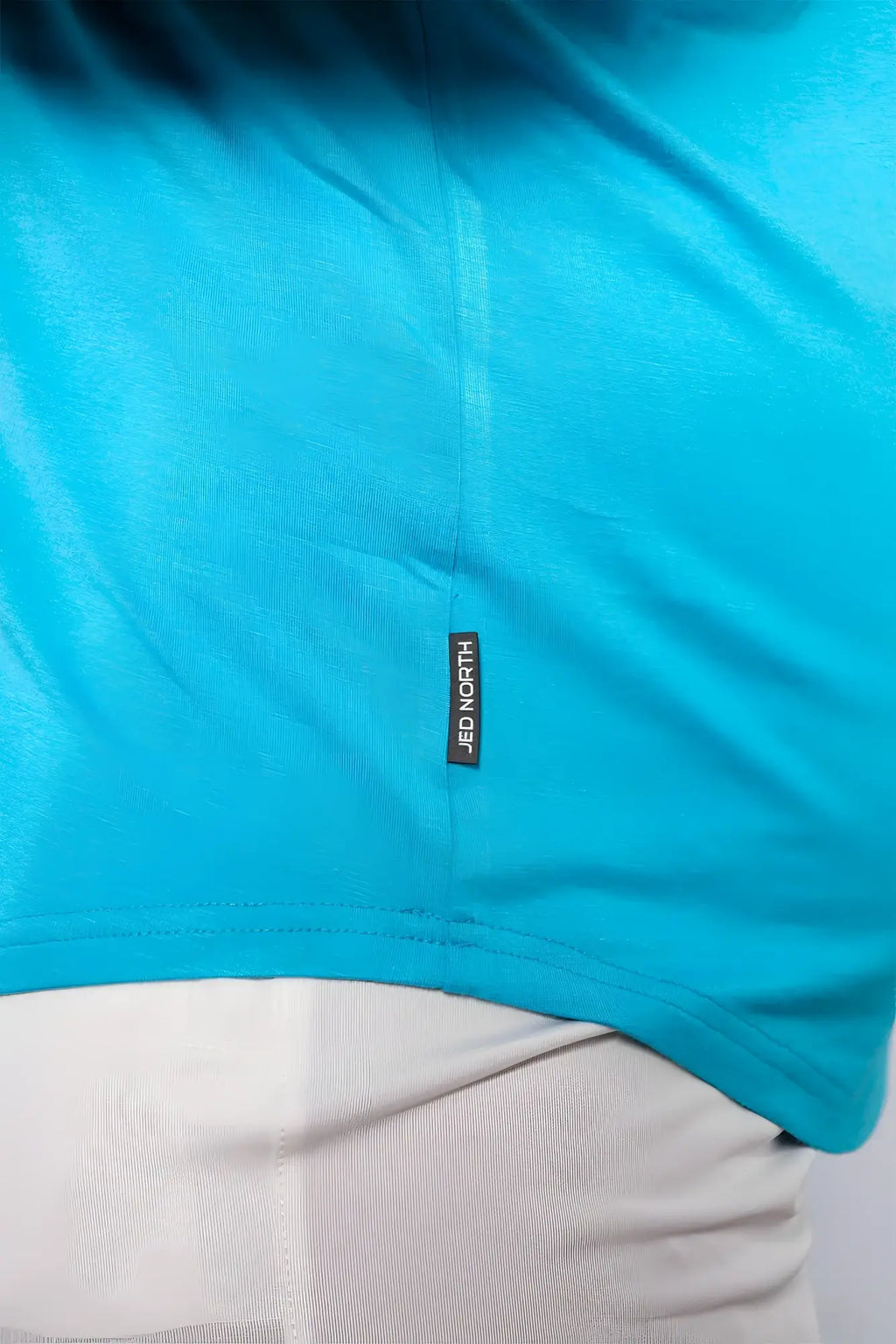 Bright turquoise short sleeved t-shirt with black jed north brand tag near hem for casual and athletic wear