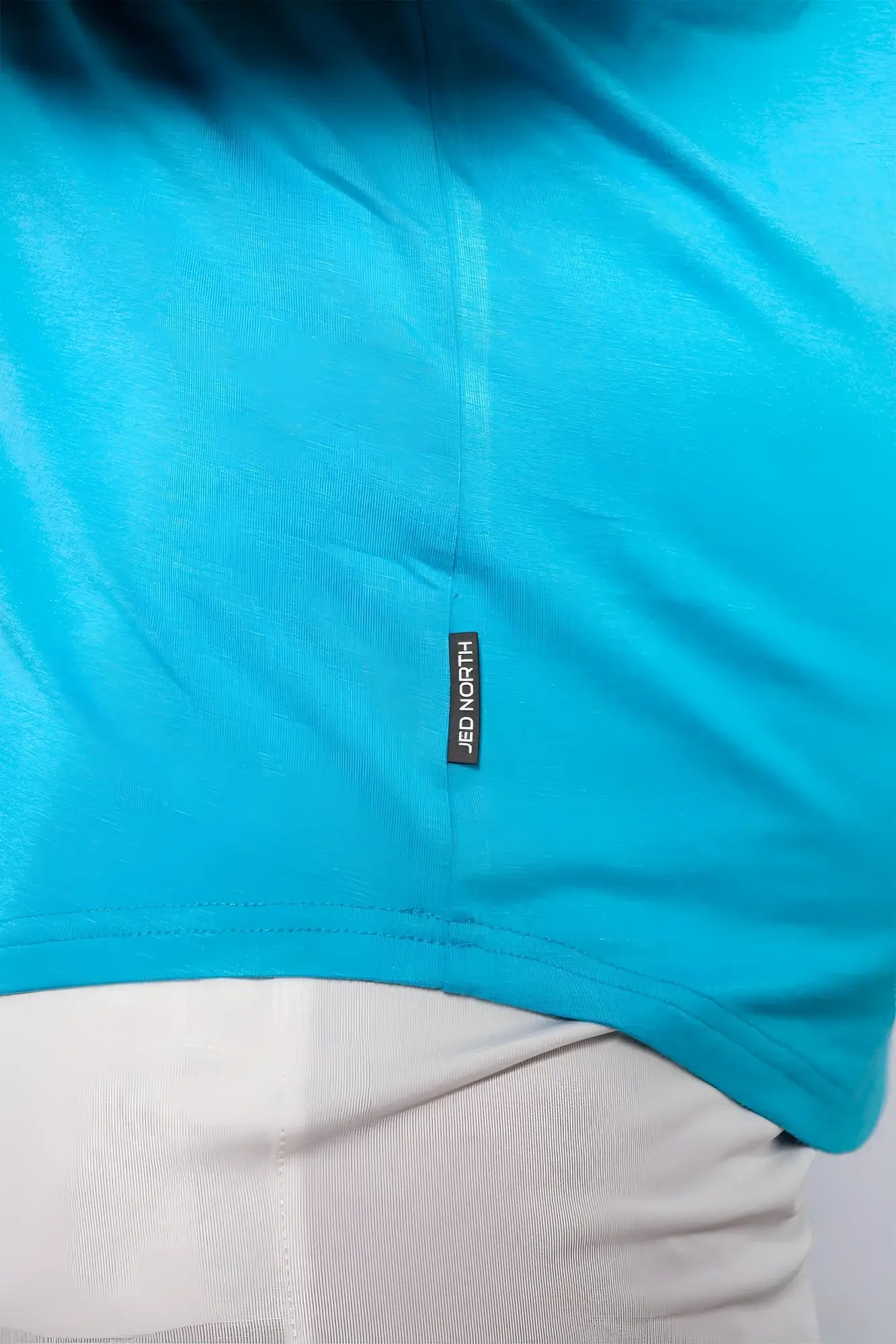 Bright turquoise short sleeved t-shirt with black jed north brand tag near hem for casual and athletic wear