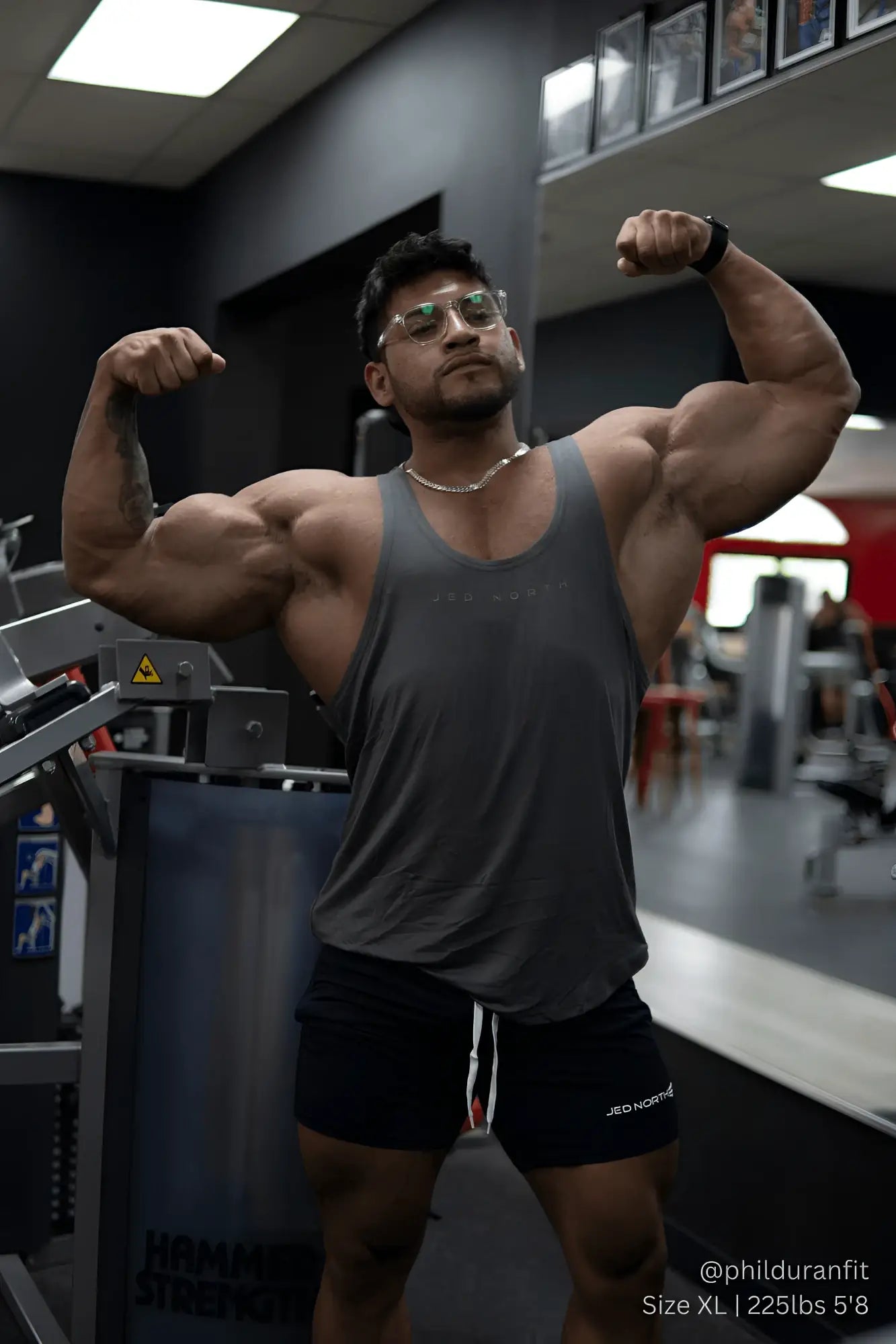 A muscular man wearing a jed north classic bodybuilding racerback stringer in steel gray at the gym