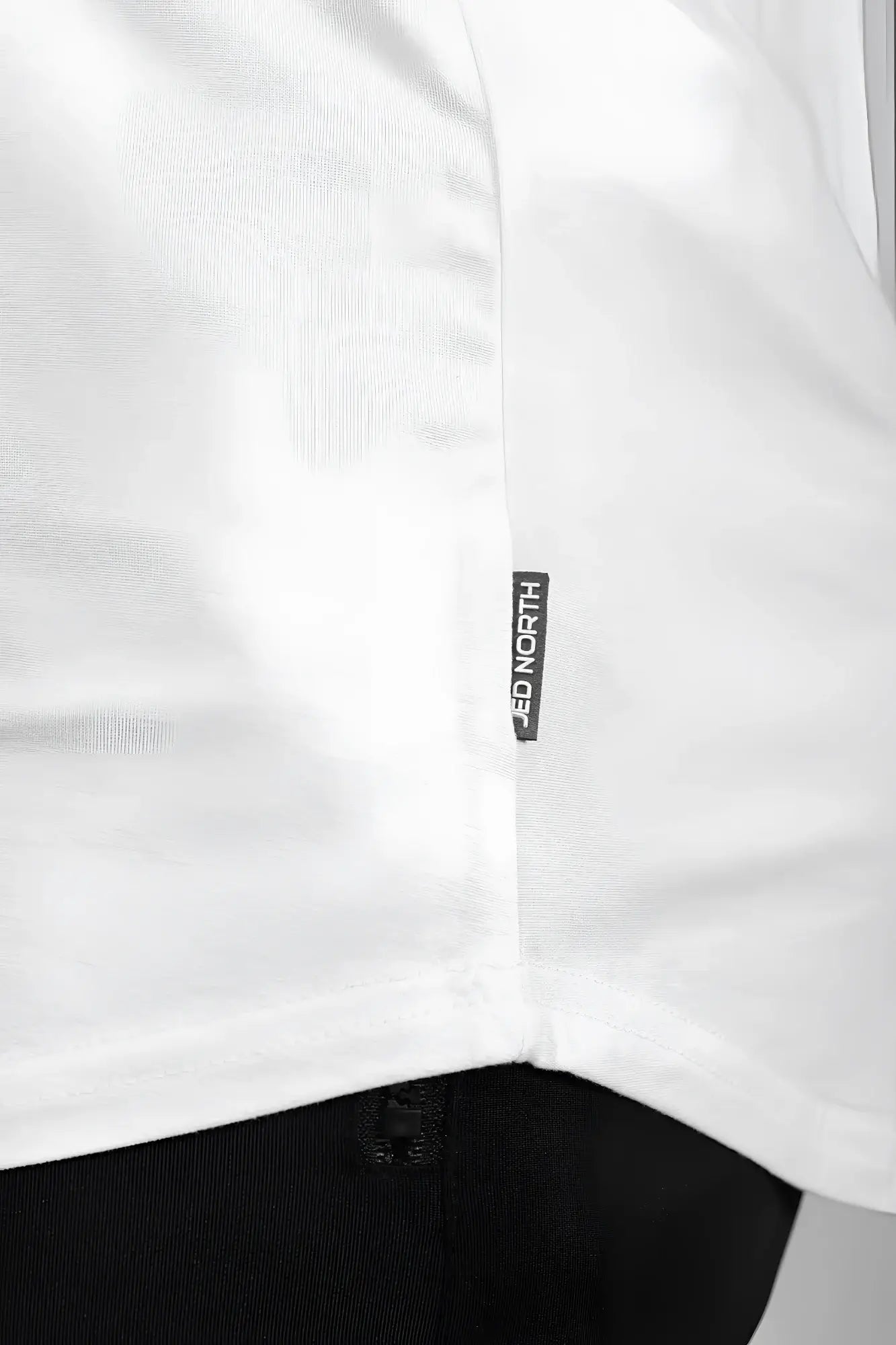 White cotton classic bodybuilding racerback stringer with a black jed north brand tag stitched near the hem
