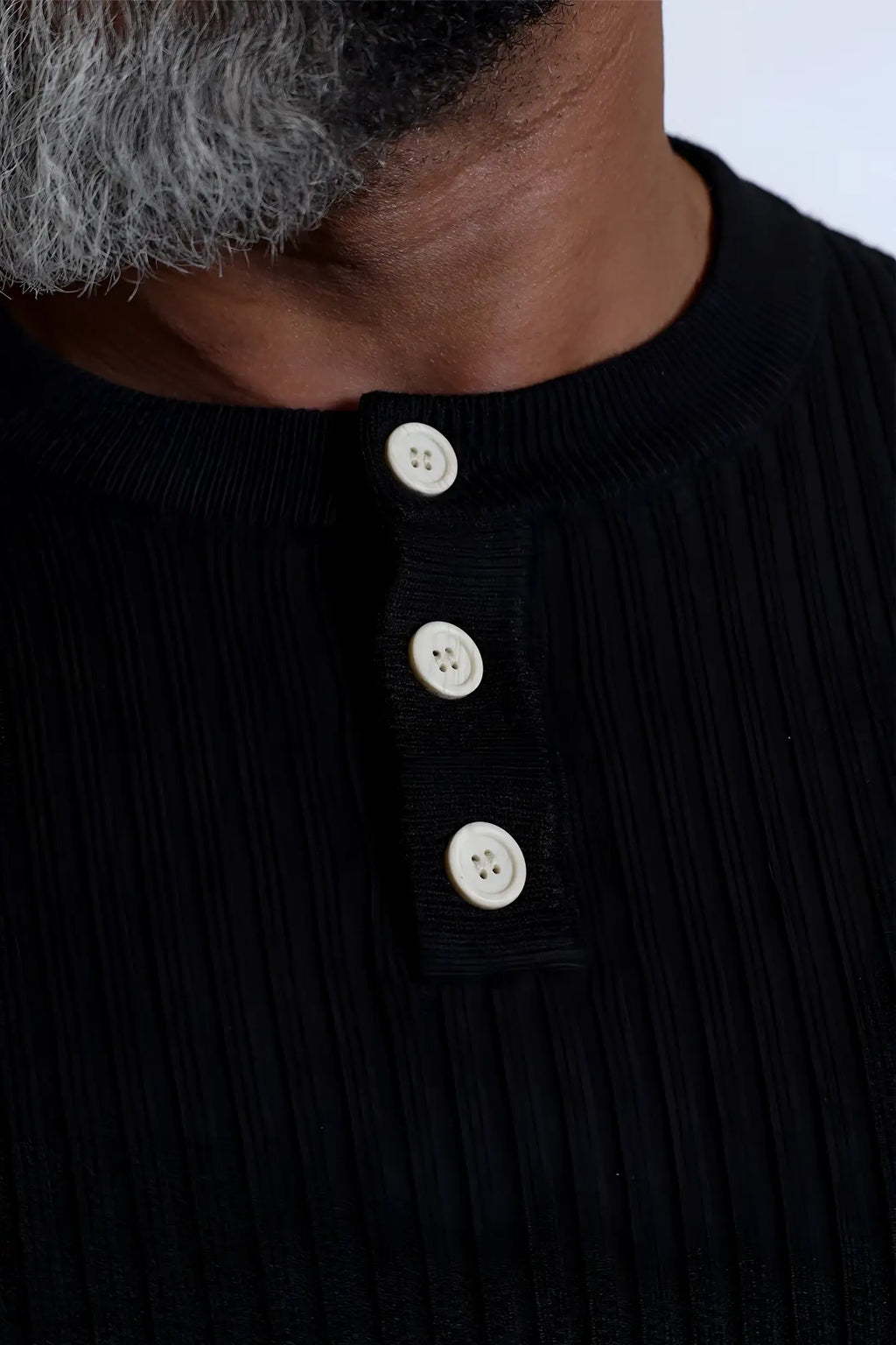 Classic henley sweater black featuring a black ribbed knit fabric with three white buttons on the front