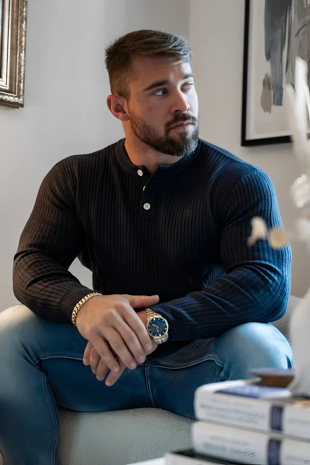 A man wearing a dark navy ribbed knit henley sweater with white button accents in classic dark gray color