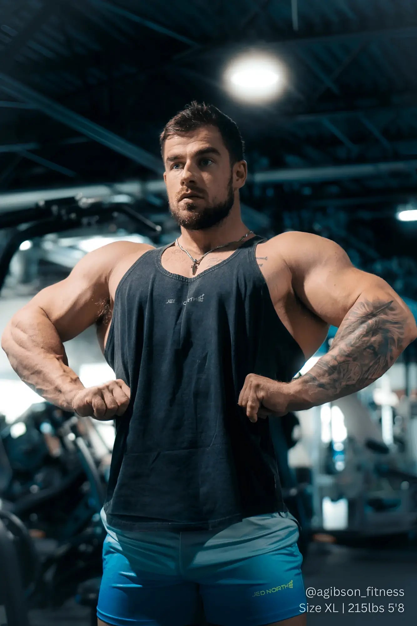 Muscular man wearing jed north classic vintage washed racerback stringer in charcoal with blue shorts