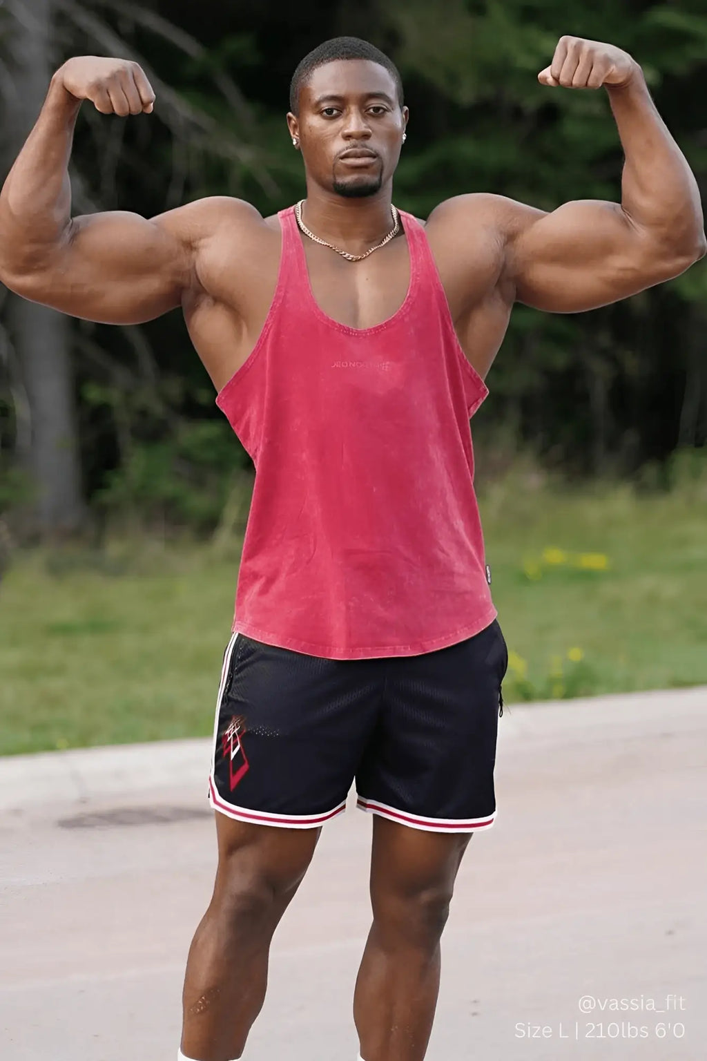 A man wearing a jed north classic vintage washed racerback stringer tank top in faded crimson with black shorts