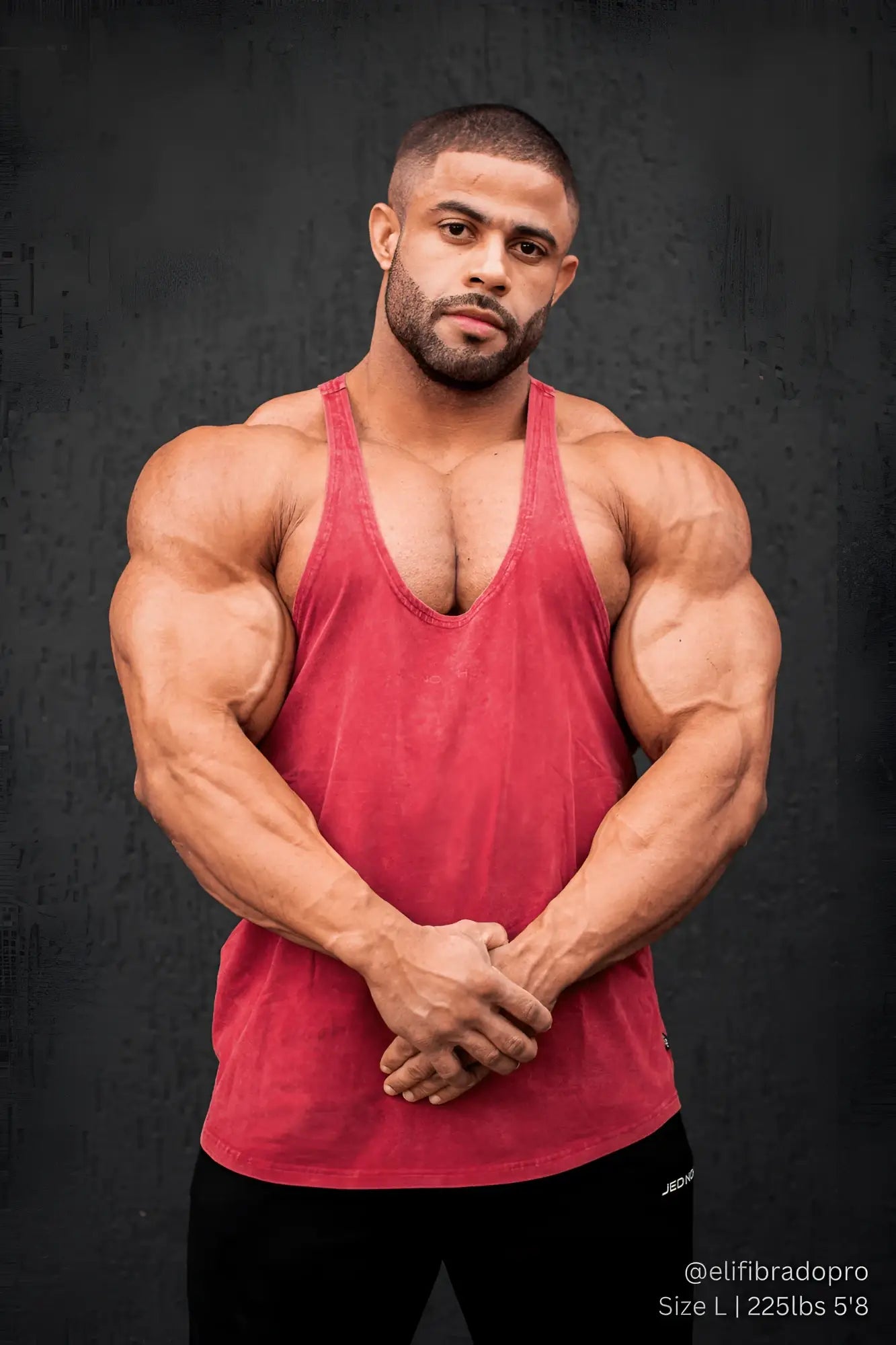 A muscular man wearing a crimson jed north classic vintage washed racerback stringer sleeveless tank top