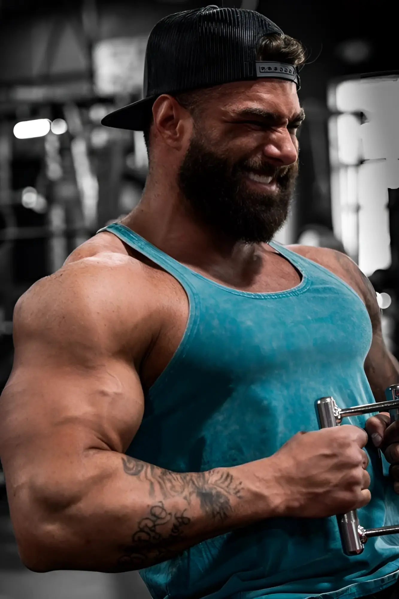 A muscular man wearing a teal jed north classic vintage washed racerback stringer deep sea while holding gym equipment