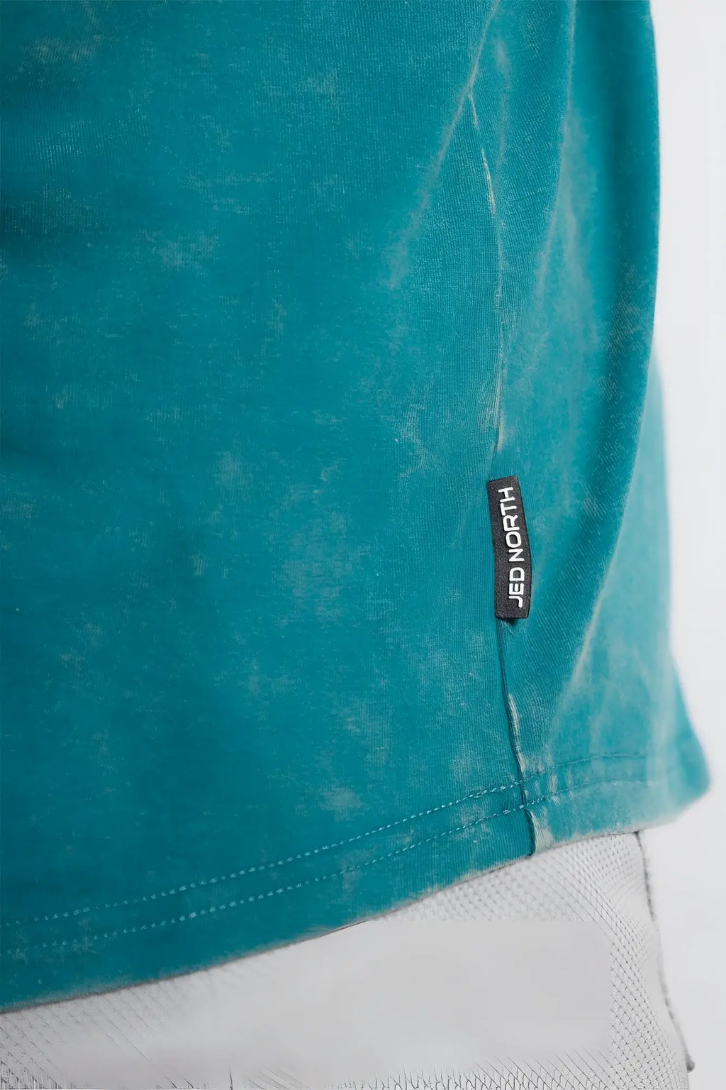 A teal faded cotton racerback stringer t shirt with a black jed north tag near the hem deep sea color
