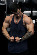 A man wearing a jed north classic vintage washed racerback stringer navy tank top showing muscle definition