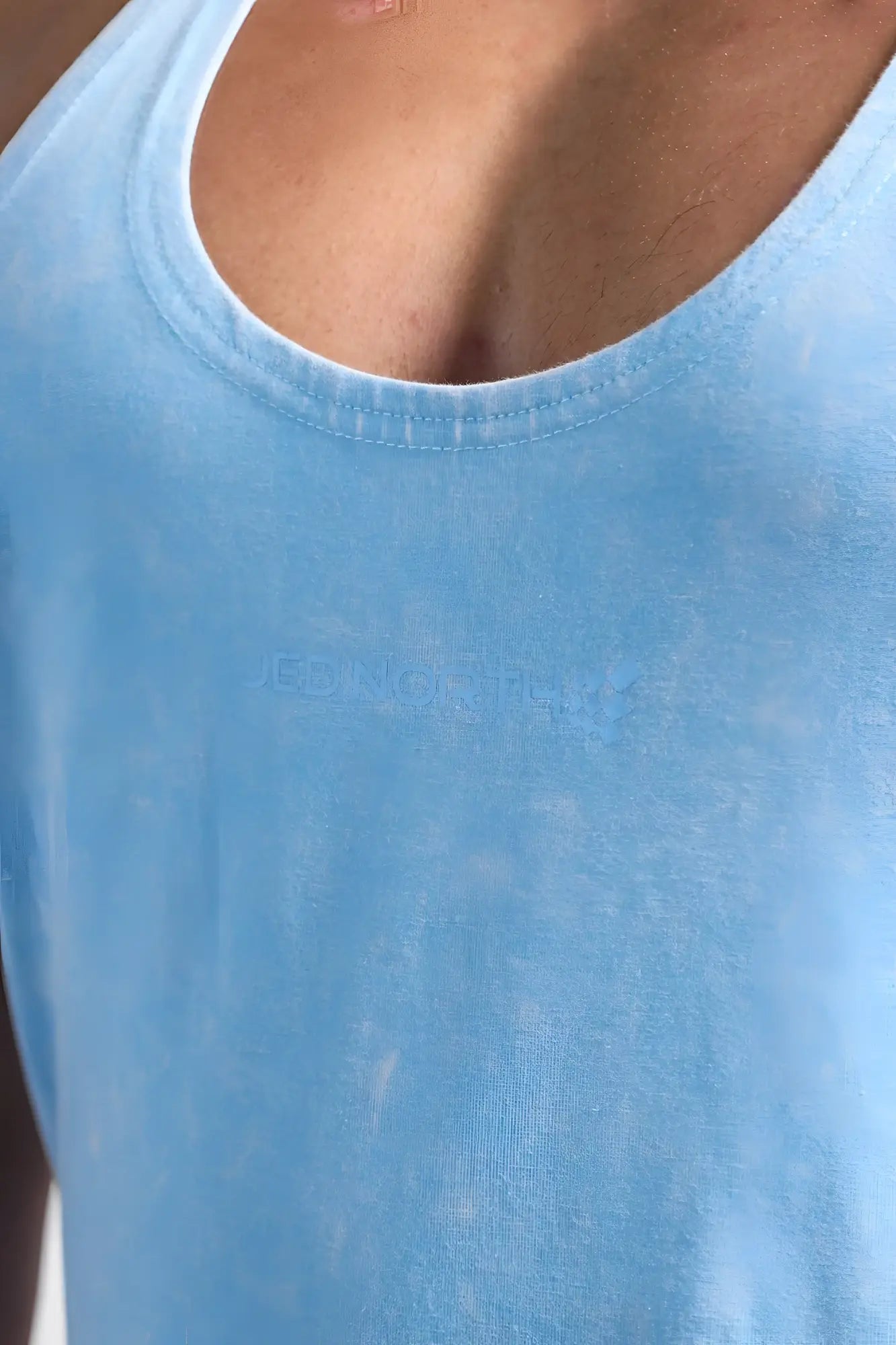 Light blue vintage washed cotton racerback stringer tank top with subtle embroidered logo across the chest
