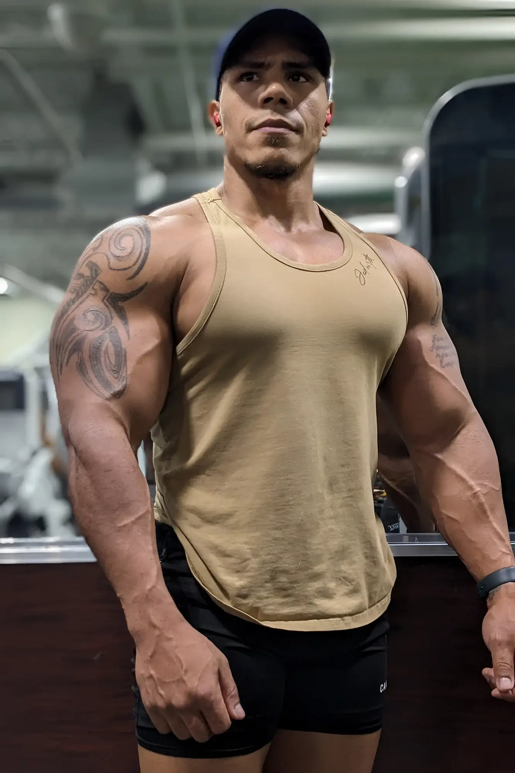 Beige sleeveless cotton training stringer tank top with subtle embroidered logo on the chest for athletic use